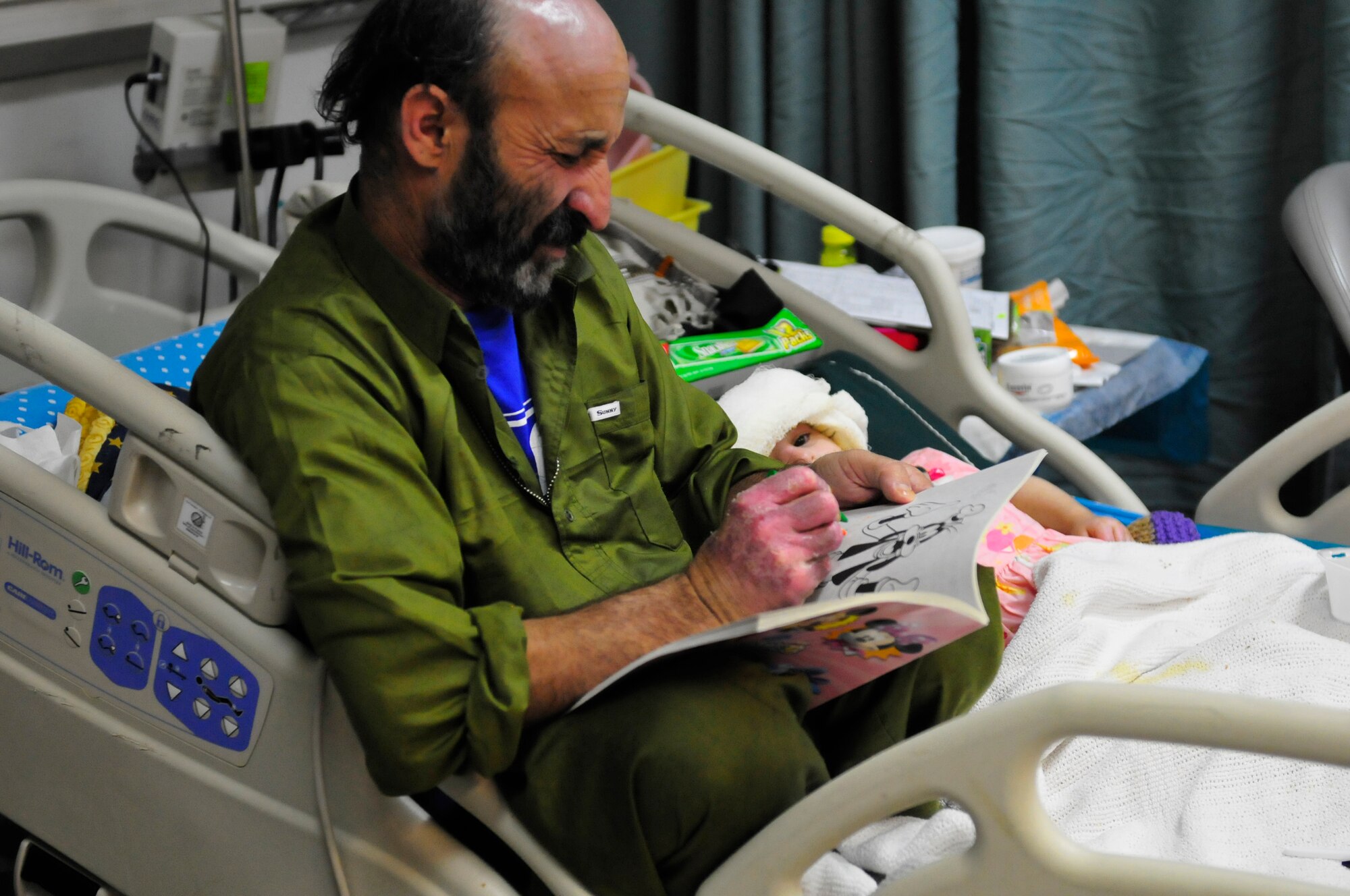 Ghulam Hazrat and his daughter Satara pass the time as patients coloring together at the Craig Joint Theater Hospital located on Bagram Airfield, Afghansitan, Jan. 10, 2011. A large majority of the Hazrat family were badly injured after the propane tank used to heat their home exploded. During the time they were treated here they have touched the hearts of many doctors and medics who interact with them each day. (U.S. Air Force photo by Tech. Sgt. Michael Voss)  