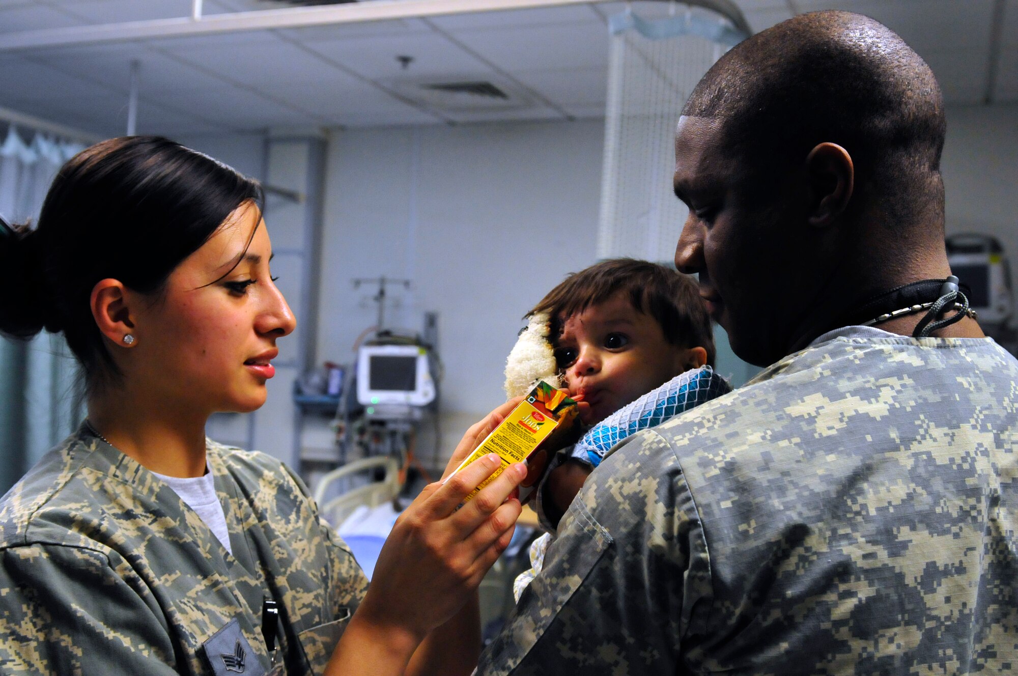 Medical technicans, Senior Airmen Mabel Aguirre and Staff Sgt. Dequijamin Roberson deployed to the 455th Expeditionary Medical Operation Squadron tend to Ajamal Hazrat a patient at the Craig Joint Theater Hospital at Bagram Airfield, Afghansitan, Jan. 10, 2011. Ajamal and a large majority of his family were badly injured after the propane tank used to heat their home exploded. Ajamal's grandfather and aunt were treated here and have touched the hearts of the doctors and medics who interact with them each day. (U.S. Air Force photo by Tech. Sgt. Michael Voss)  