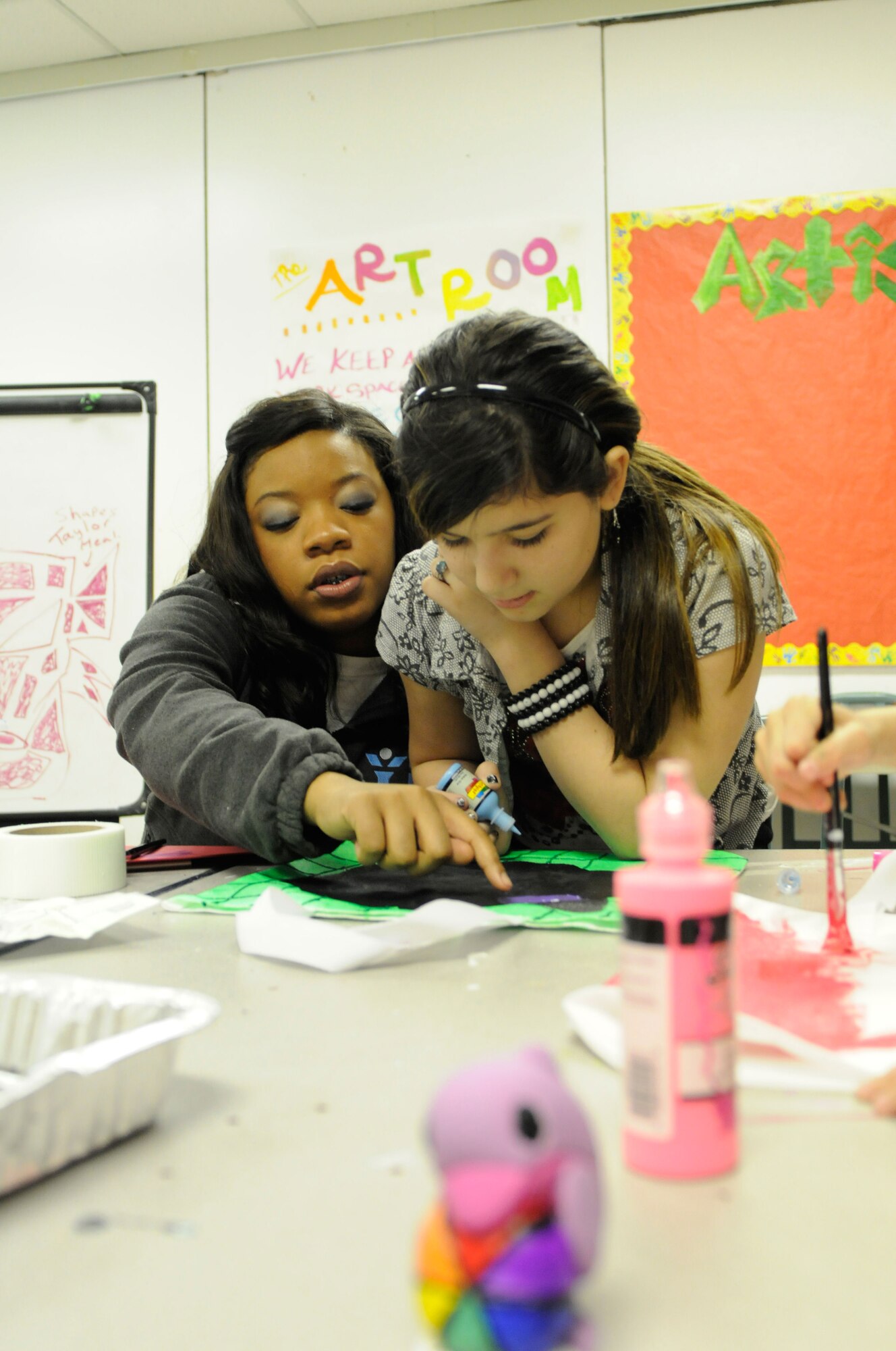 Andrea Robins, program assistant,helps Natalie Korkmaz, in creating her new tote bag at Kennecott Youth Center, Jan. 7. JBER youth centers offer field trips,sports, dances and study hall. (U.S. Air Force photo/Steve White)