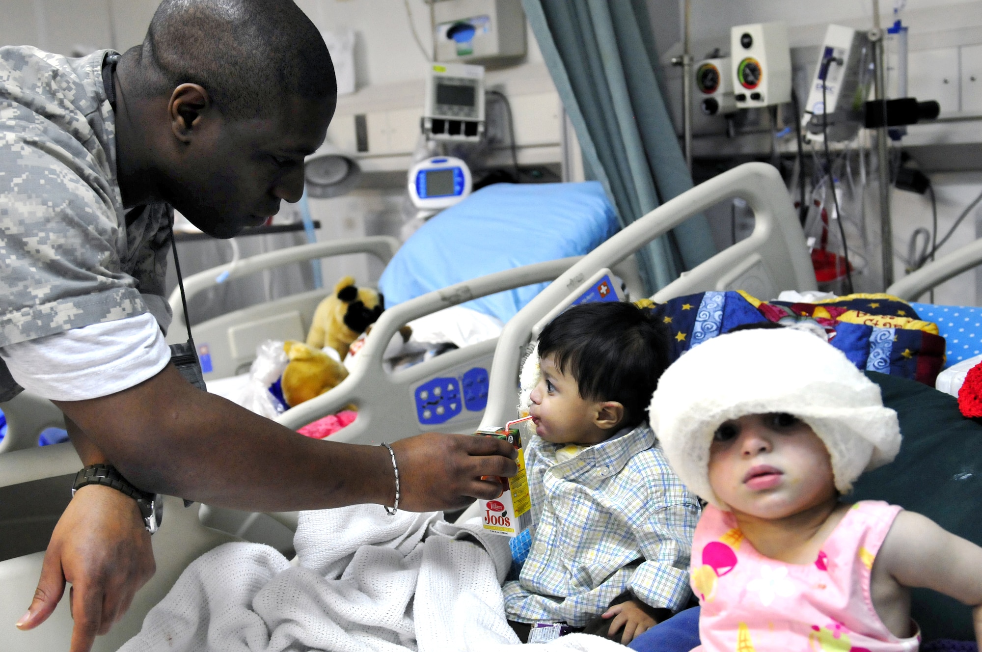 Staff Sgt. Dequijamin Roberson tends to Ajamal and Satara Hazrat Jan 9, 2011. The two were patients at the Craig Joint Theater Hospital at Bagram Airfield, Afghanistan, after they and several family members were badly injured when a propane tank used to heat their home exploded. Sergeant Roberson is a medical technician assigned to the 455th Expeditionary Medical Operation Squadron.  (U.S. Air Force photo/Tech. Sgt. Michael Voss)