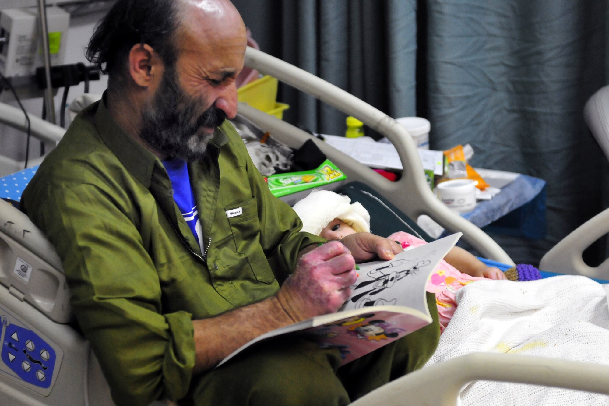 Ghulam Hazrat and his daughter, Satara, pass the time in recovery Jan 10, 2011, at the Craig Joint Theater Hospital at Bagram Airfield, Afghanistan.  Several members of the Hazrat family were badly injured after a propane tank used to heat their home exploded.  (U.S. Air Force photo/Tech. Sgt. Michael Voss)
