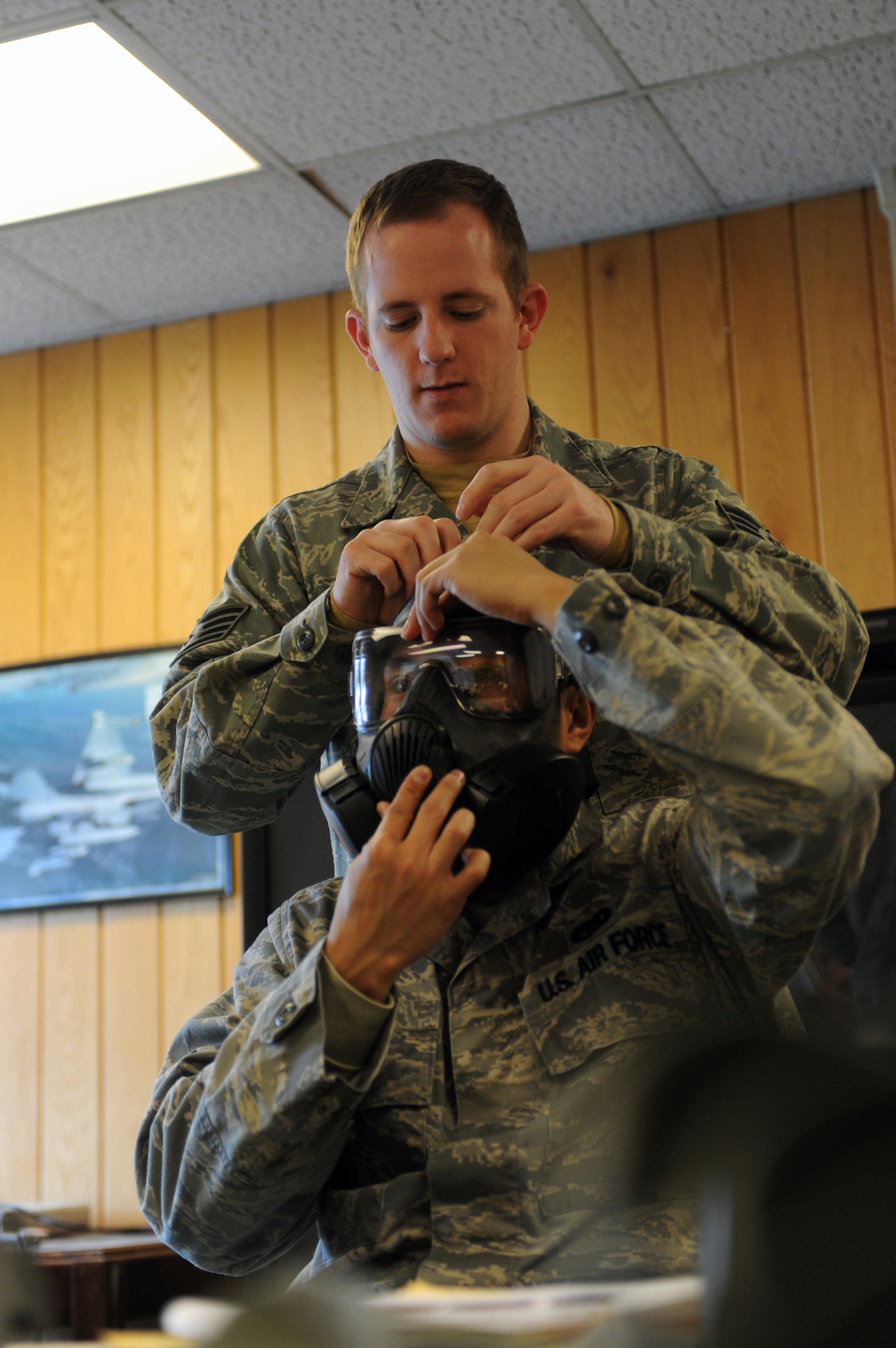 MINOT AIR FORCE BASE N.D. -- Staff Sgt. Alexander Rexroad, 5th Civil Engineer Squadron emergency management logistics journeyman, demonstrates how to tighten the M-50 gas mask on First Lt. Jon Arceta, 5th Logistics Readiness Squadron installation deployment officer, here Jan 5.  Minot Air Force Base is the first base in Air Force Global Strike Command to receive and issue the new M-50 gas mask. (Air force photo/Airman 1st Class Aaron-Forrest Wainwright)