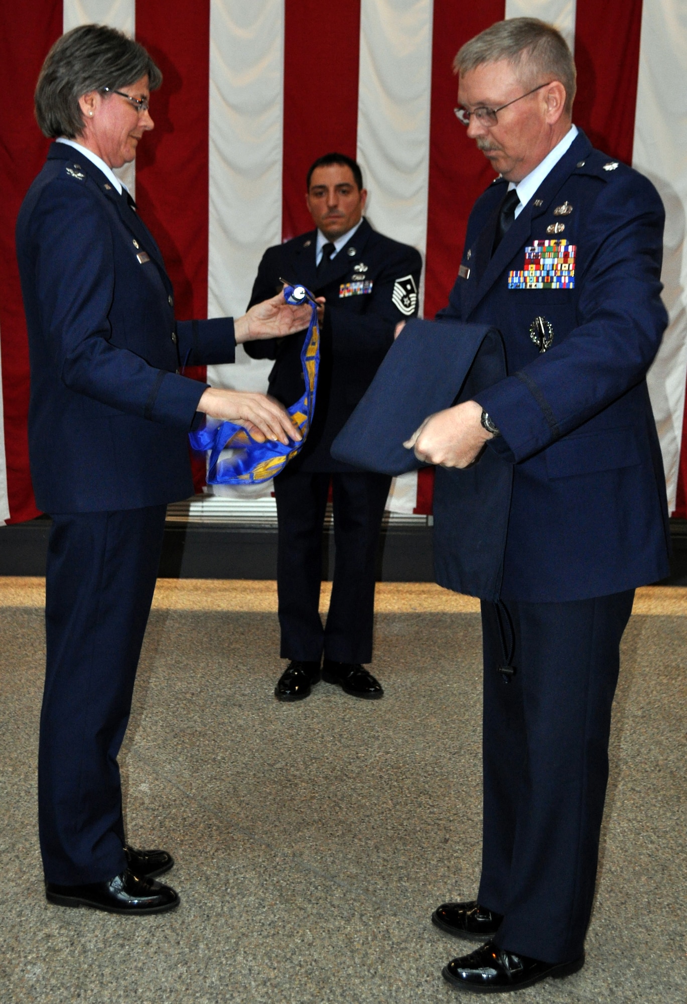 TRAVIS AIR FORCE BASE, Calif. -- Col. Nancy Brooks, commander, 349th Mission Support Group, unrolls the new 349th Force Support Squadron flag with the help of Lt. Col. Neal Landeen, commander, 349th Force Support Squadron and Master Sergeant Mark Eger, first sergeant, 349th Force Support Squadron during a redesignation ceremony helf here on January 8, 2011. (U.S. Air Force photo/Senior Airman Amelia Leonard)