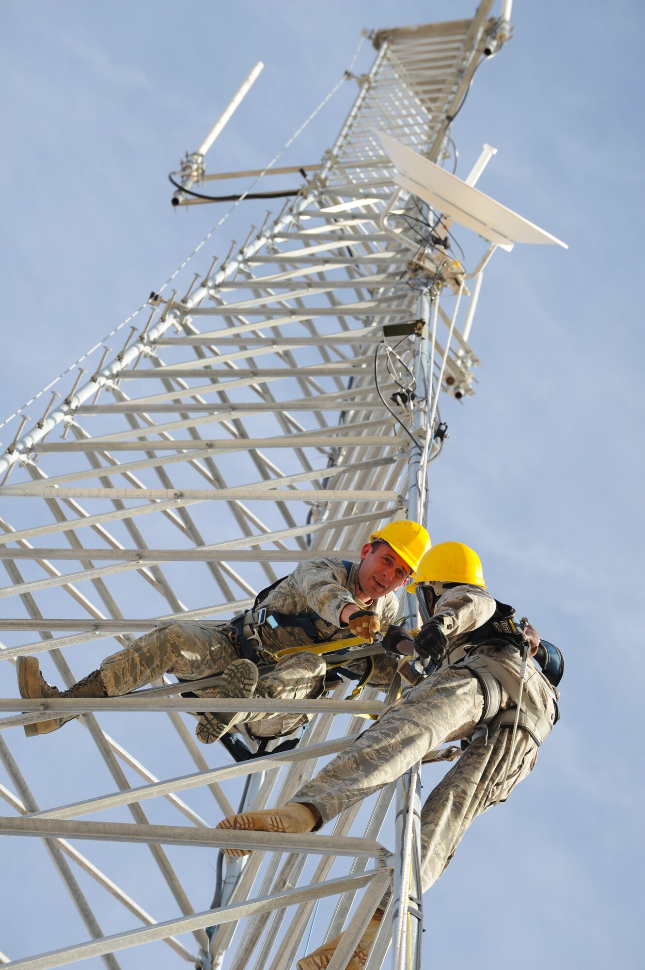 HOLLOMAN AIR FORCE BASE, N.M. -- Airmen 1st Class Patrick Holland and Justin Bowden, both from the 49th Communication Squadron, hand each other tools on a radio tower at the land mobile radio shop Jan. 7, 2011. The Airmen were aligning a point-to-point shot, connecting the base's Network Control Centers. The radio tower also serves as a back-up satellite if the base should lose connectivity to the internet. (U.S. Air Force photo by Airman 1st Class Eileen Payne/Released)