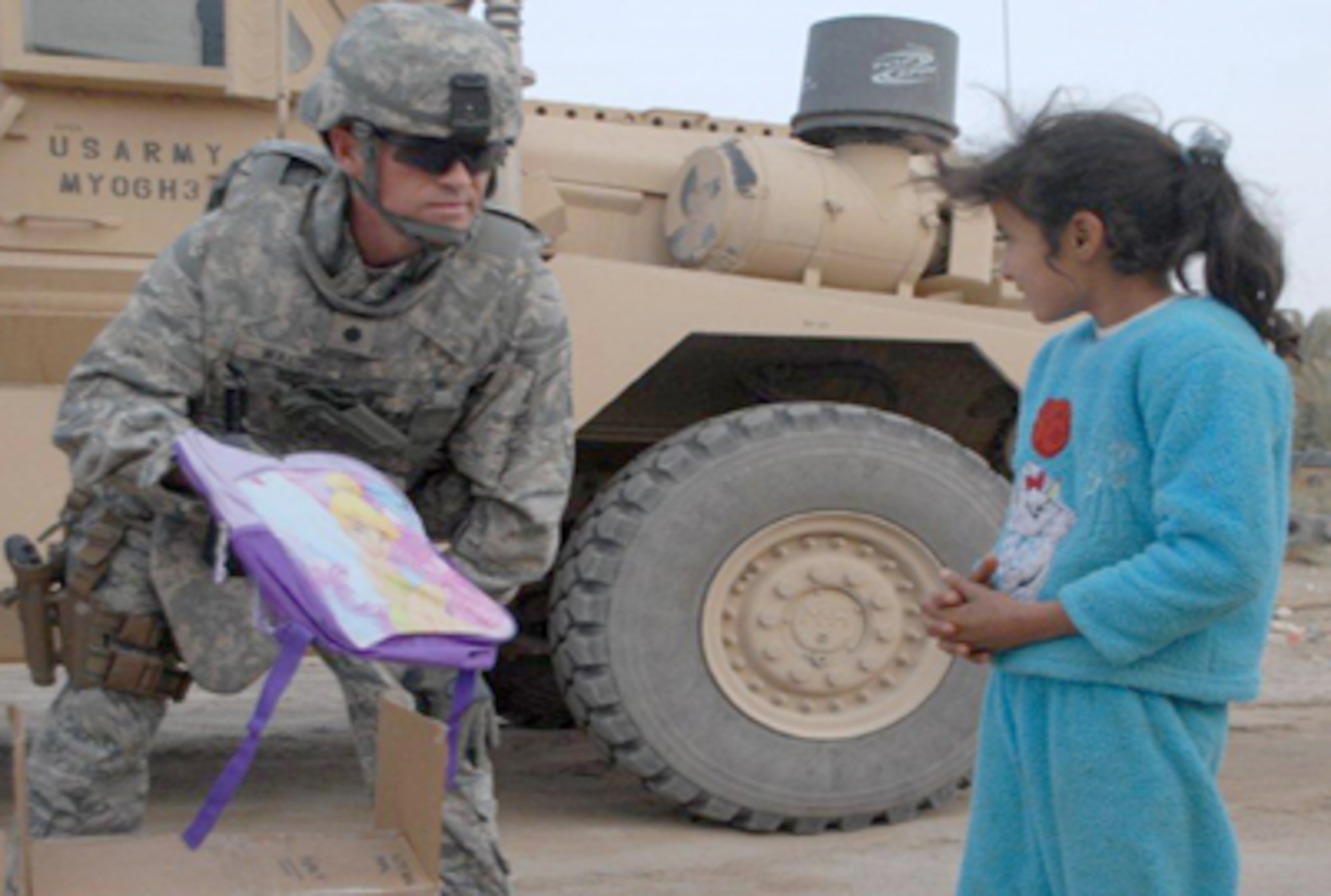 Lt. Col. Tom Walsh hands a backpack to an Iraqi girl Dec. 16, 2010, at Ur Elementary School near Tallil Air Base, Iraq. Colonel Walsh is an Echelon Above Division-Advise and Train senior adviser. (U.S. Army photo/Spc. Chastity Boykin) 