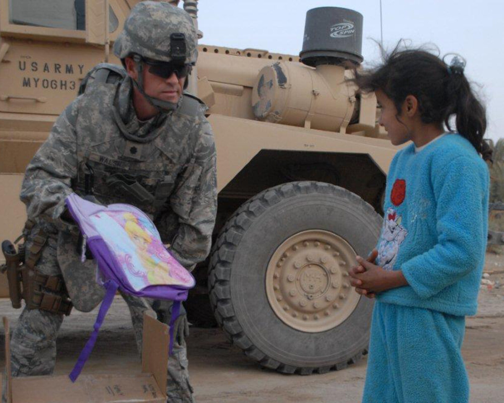 U.S. Air Force Lt. Col. Tom Walsh, Echelon Above Division-Advise and Train senior advisor and Benbrook, Texas, native, hands a “tinkerbell” backpack to a local Iraqi girl Dec. 16 at Ur Elementary School near Tallil Air Base, Iraq. Colonel Walsh is deployed from the Pentagon. (U.S. Army photo by Spc. Chastity Boykin)