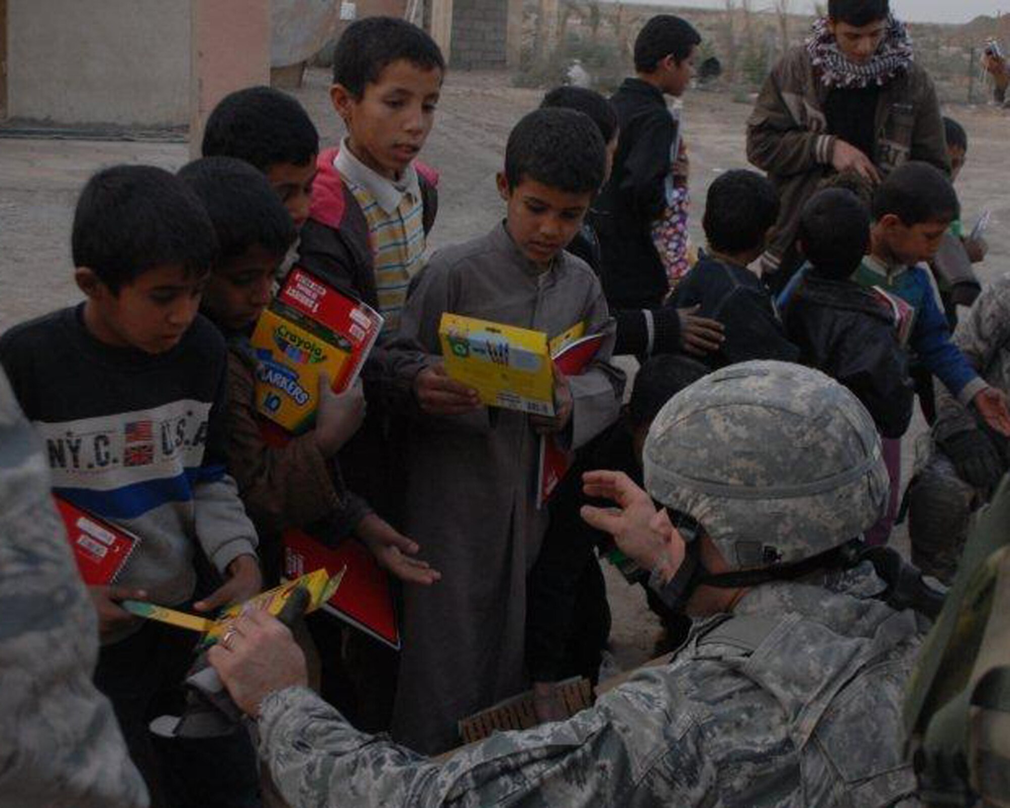 U.S. Air Force Master Sgt. Brent Baker, Echelon Above Division-Advise and Train munitions advisor and Fairport, N.Y., native, hands markers and crayons to local Iraqi children Dec. 16 at Ur Elementary School near Tallil Air Base, Iraq. Sergeant Baker is deployed from Minot Air Force Base, N.D. (U.S. Army photo by Spc. Chastity Boykin)