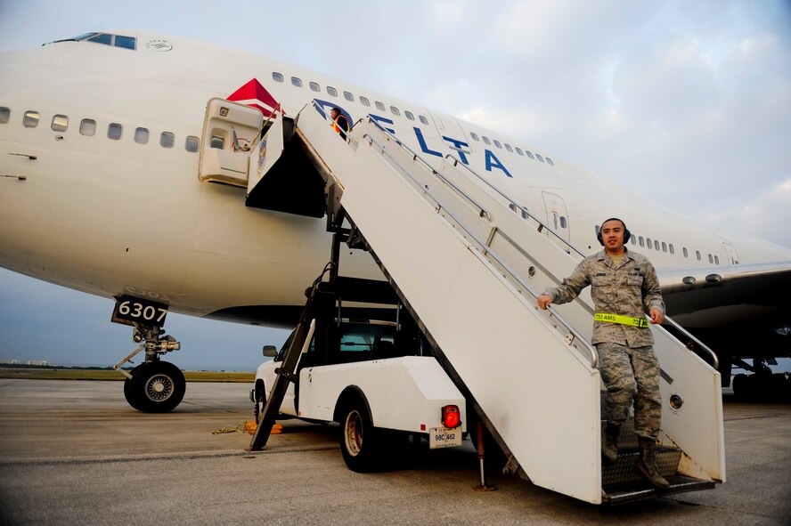 Airman 1st Class Jess Dureza, 733rd Air Mobility Squadron, walks down the stairs leading to an airliner full of Marines from the 3rd Marine Expeditionary Force on Kadena's flight line Jan 6.  The Air Force provided the 3,000 Marines from the 3rd MEF with lodging, dining facilities, transportation and other services, in support of their movement through Kadena's Air Mobility Command Passenger Terminal. (U.S. Air Force photo/Staff Sgt. Jonathan Steffen)