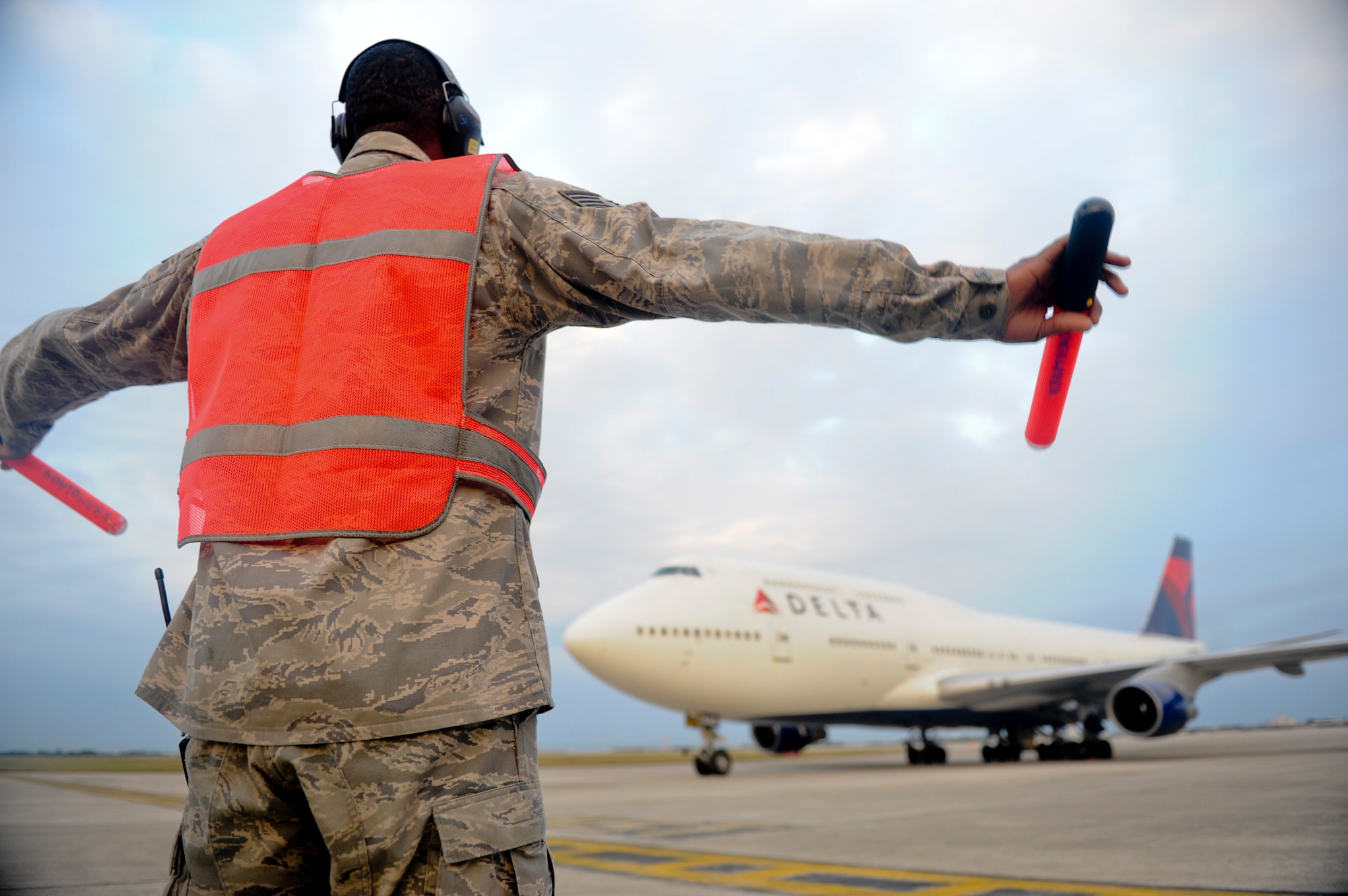 Staff Sgt. Samuel Owens, 733rd Air Mobility Squadron, guides a Boeing 747 full of Marines from the 3rd Marines Expeditionary Force onto Kadena's flight line Jan. 6. The Airmen from the 733rd AMS and 18th Logistic Readiness Squadron, Installation Deployment Readiness Cell, coordinated the Marines' movement through the base by providing lodging, transportation, dining facilities and other services. (U.S. Air Force photo/ Staff Sgt. Jonathan Steffen)