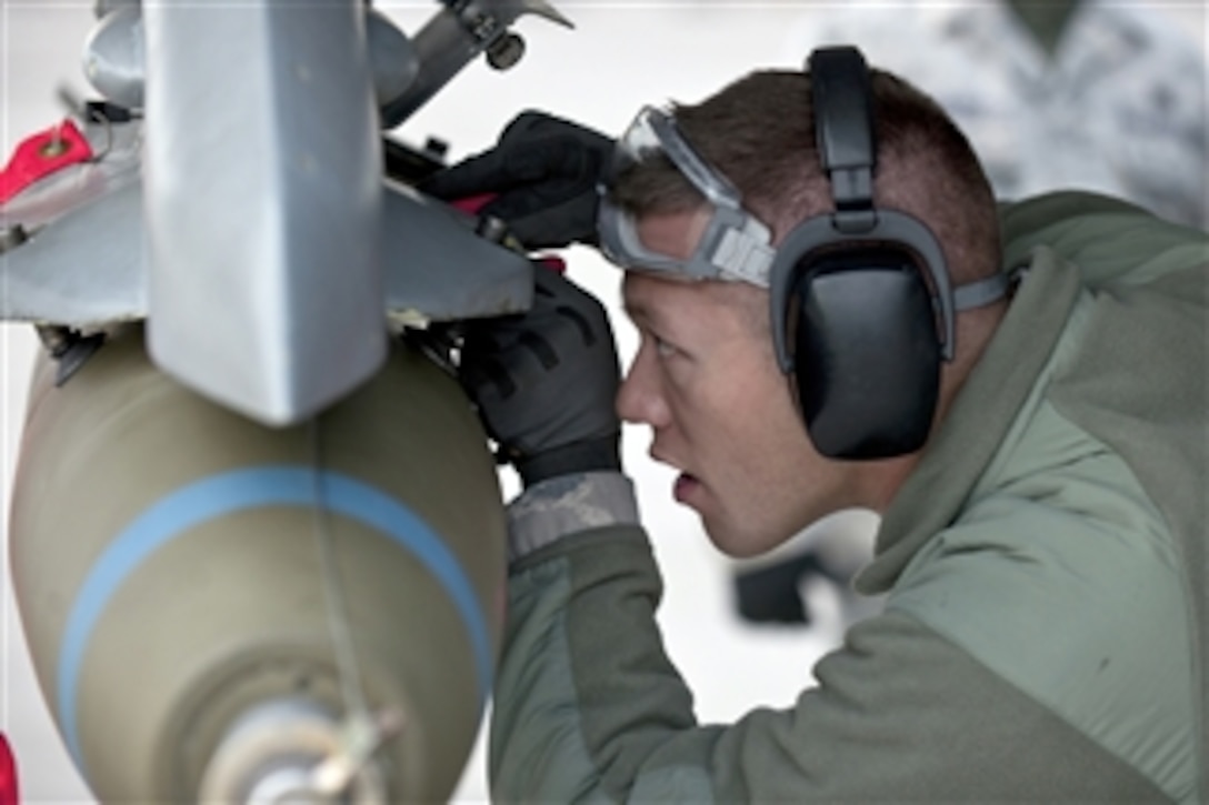 Airman 1st Class Lucas Wolf secures an MK-82 bomb on an F-16 Fighting Falcon aircraft during a weapons load competition at Nellis Air Force Base, Nev., on Jan. 7, 2011.  Weapons load competitions are conducted quarterly to keep airmen sharp and to recognize superior performers.  Weapons load teams are evaluated for their use of the checklist, safety and overall speed.  Wolf is an aircraft armament systems apprentice with the 57th Aircraft Maintenance Squadron.  