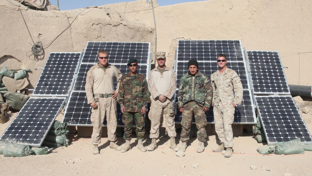 Marines and sailors of India Company, 3rd Battalion, 5th Marine Regiment, and their Afghan national army counterparts, pose in front of a modified ZeroBase Regenerator at Patrol Base Sparks, in Sangin District, Dec. 29. The ZeroBased Regenerator, nicknamed “the Raptor,” after the type of power cells in its six solar panels, can keep more than 17 computers and 15 lighting units running throughout the night. The Marines of 1st Platoon, added four more panels to their “Raptor” for further solar energy conservation.