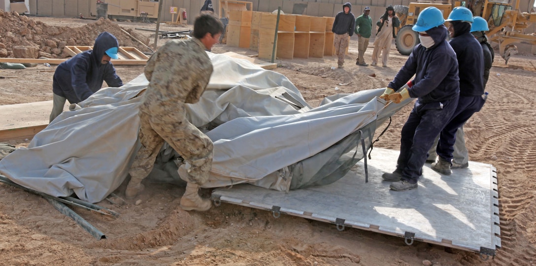A member of the Afghanistan National Police helps civilian contractors remove pieces of an old internet tent center in order to make room for a new one during the construction of Logcamp at Camp Hanson, in Marjah, Helmand province Afghanistan, Jan. 13. Once complete, Logcamp will consist of 36 state-of-the-art all-weather tents, fully functional bathrooms and showers, and a brand new internet and recreation center.