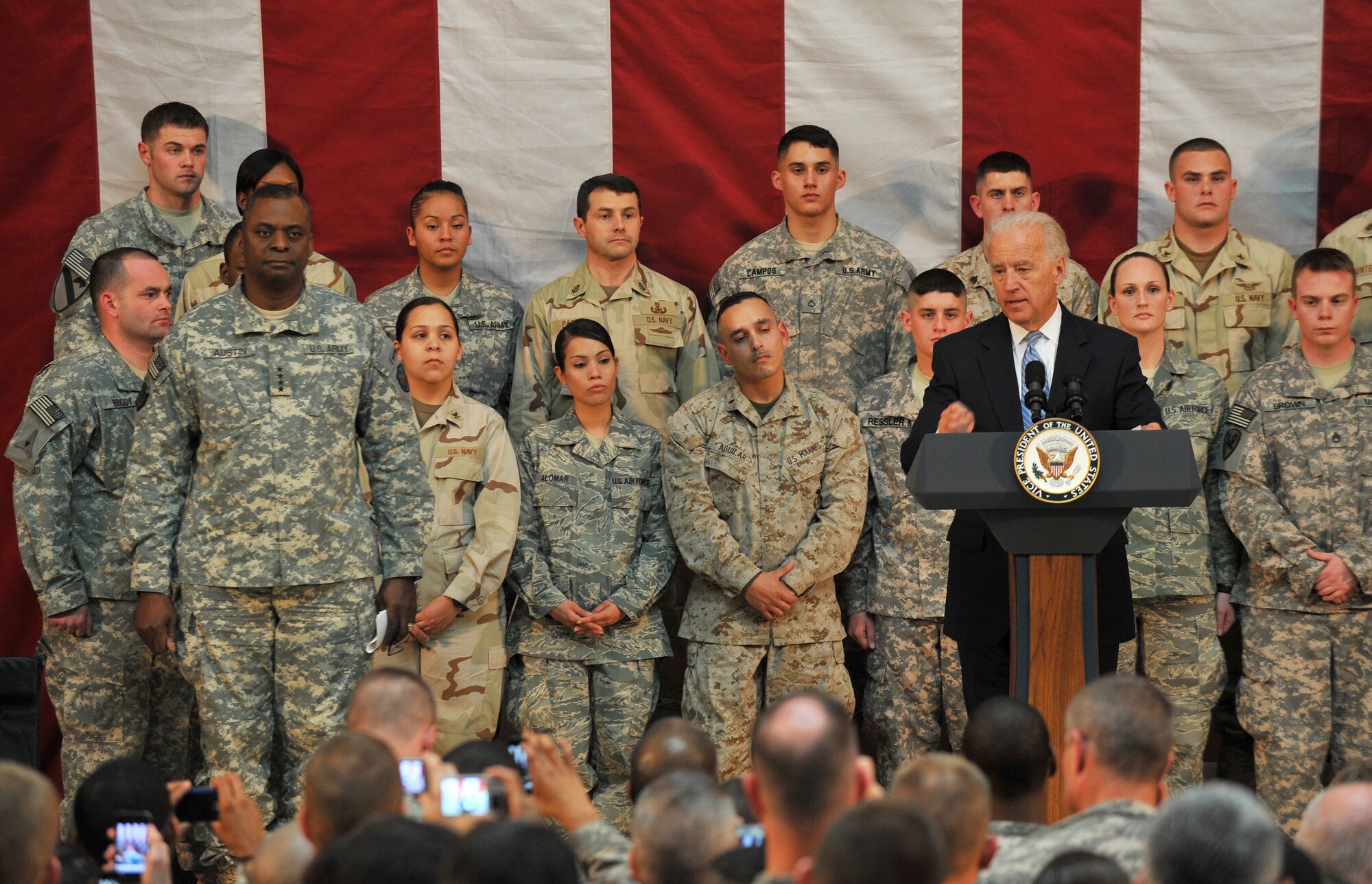 Vice President Joe Biden speaks to a crowd of more than 200 servicemembers and civilians as Staff Sgt. Pearl Alomar (standing in the front row, third to the left of the vice president) listens to his message of thanks and his appreciation for military members and their families Jan. 13 on Camp Victory, Iraq. Sergeant Alomar was one of five Airmen standing behind the vice president as he spoke. U.S. Air Force photo by Senior Airman Andrew Lee)