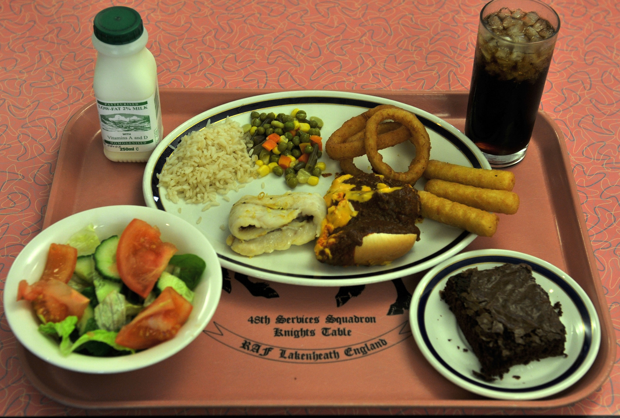 Which half of this tray does your lunch look like? On the healthy side, we have salad, steamed rice, a small piece of fish and milk. On the unhealthy side, there's a chili cheese dog, fried onion rings and cheese sticks, cola and a brownie. Choose wisely. (U.S. Air Force photo/Senior Airman David Dobrydney)