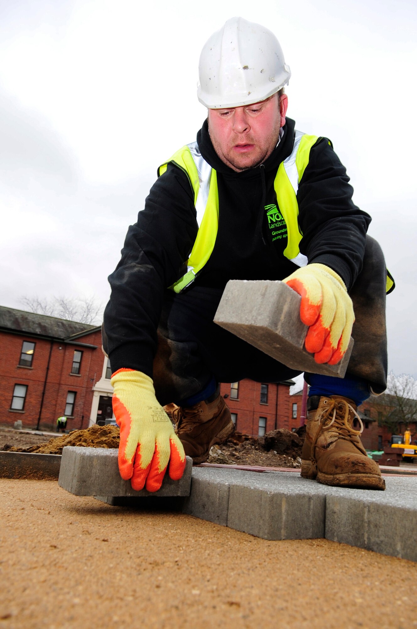 RAF MILDENHALL, England -- Wayne Noble, a local contractor, block paves one of the paths being constructed throughout Washington Square Jan. 11, 2011. The Washington Square project will contribute to the Air Force initiatives for going green by removing hard surfaces that contribute to storm water pollution and reducing vehicular pollution caused by driving through the campus. (U.S. Air Force photo/Senior Airman Ethan Morgan)