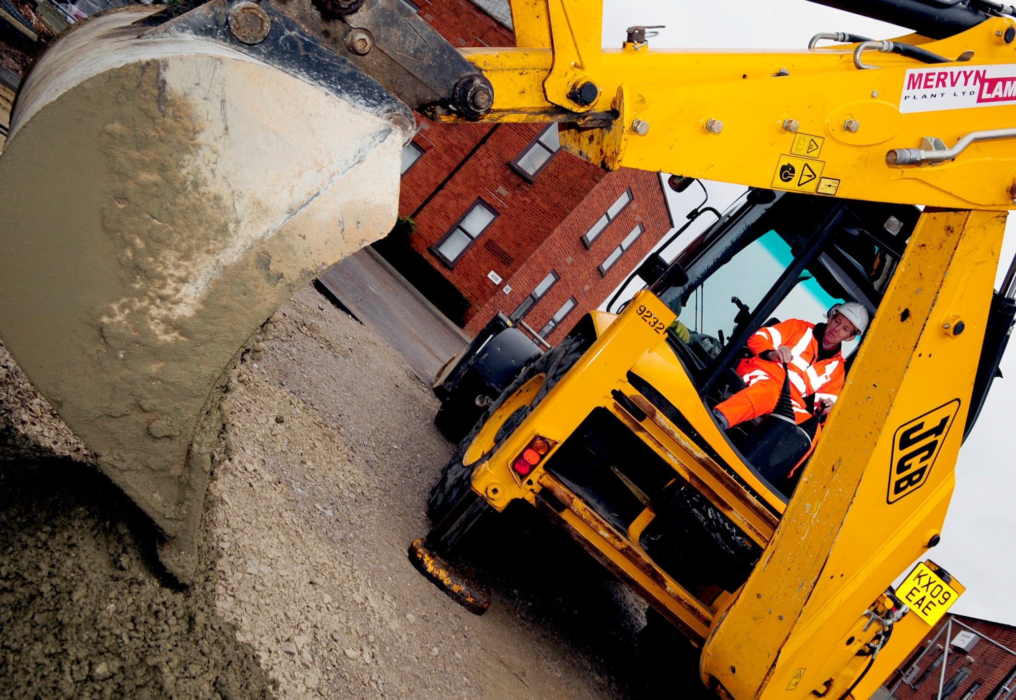 RAF MILDENHALL, England -- David Dodge, a local contractor, uses a backhoe to pour concrete for the base of edgings as part of the Washington Square construction Jan. 11, 2011. The edgings are used as the sidings and framework for the walkways being constructed in Washington Square. (U.S. Air Force photo/Senior Airman Ethan Morgan)