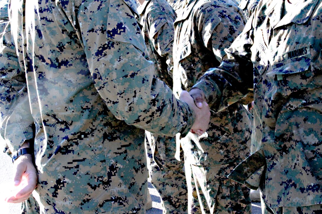 A new Marine shares his first handshake as a Marine with his drill instructor. After the drill instructor presents the eagle, globe and anchor emblem, they share the title of Marine.