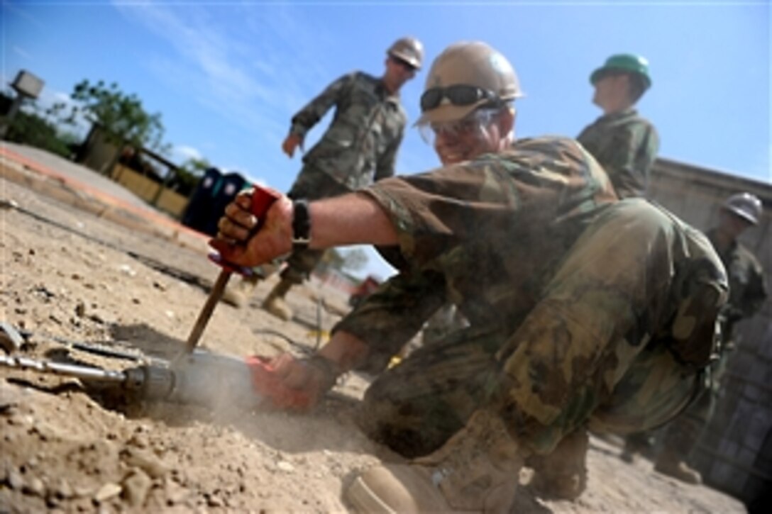 U.S. Navy Petty Officer 2nd Class Joshua L. Helton, foreground, drills a hole in the foundation of a new classroom being built at the Jacobo Vera school in Manta, Ecuador, Jan. 11, 2011. The effort is part of Southern Partnership Station, in which troops deploy to the Caribbean and Central America areas to share information with military services and civilians throughout the region.