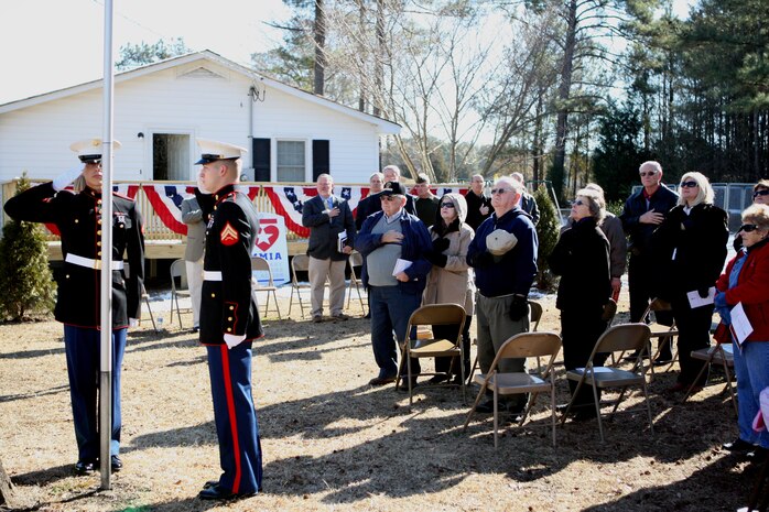 Attendants to the Cottrell house dedication render honors to the raised flag as part of the dedication ceremony in Beulaville, N.C., Jan. 14. After a 30-day renovation, Warren Cottrell, a medically-retired sergeant with Post Traumatic Stress Disorder and Traumatic Brain Injury, and his family moved into the new house as the community's volunteers looked on.