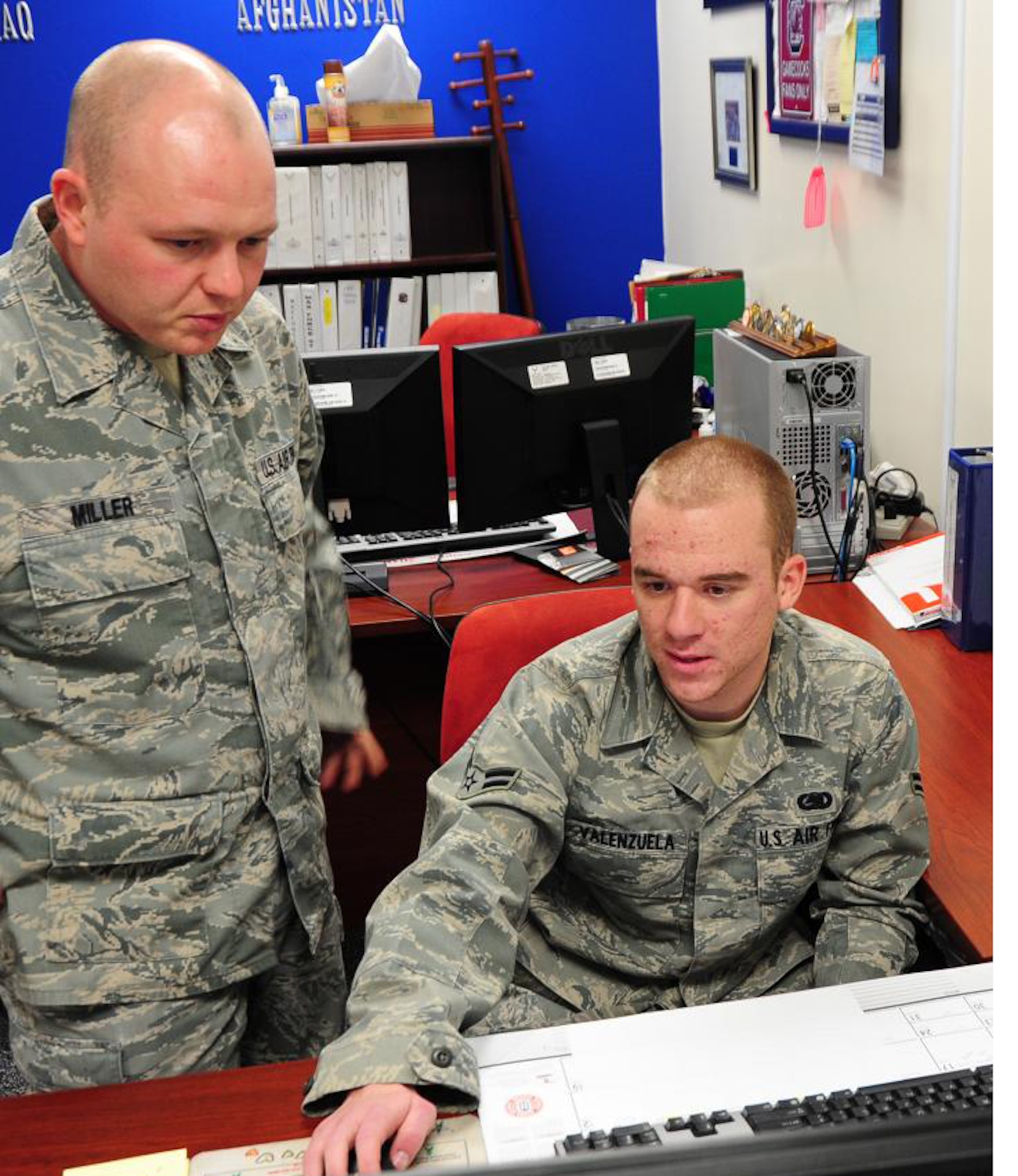 Logistics planners Staff Sgt. Patrick Miller and Airman 1st Class Shawn Valenzuela discuss upcoming deployments and short-notice taskings Jan. 6. The logistics plans career field is now accepting cross-trainee applications. (Air Force photo/Airman 1st Class Christopher Stoltz)