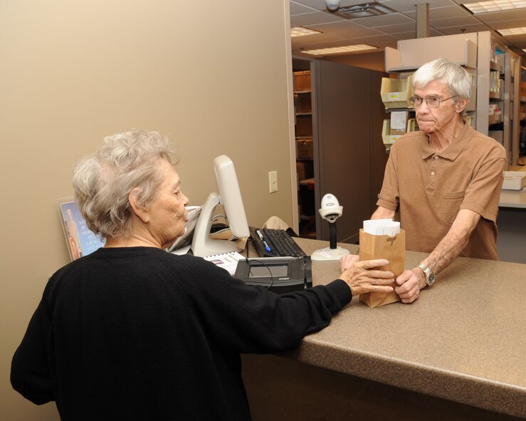 John Hefner, 2nd Medical Support Squadron volunteer, hands a patient her prescription at the base pharmacy on Barksdale Air Force Base, La., Jan. 14. The base pharmacy is in charge of handling all of the medications that are needed to treat the active duty, reserve and retiree population of Barksdale and the local community. (U.S. Air Force photo/Airman 1st Class Sean Martin)(Released)