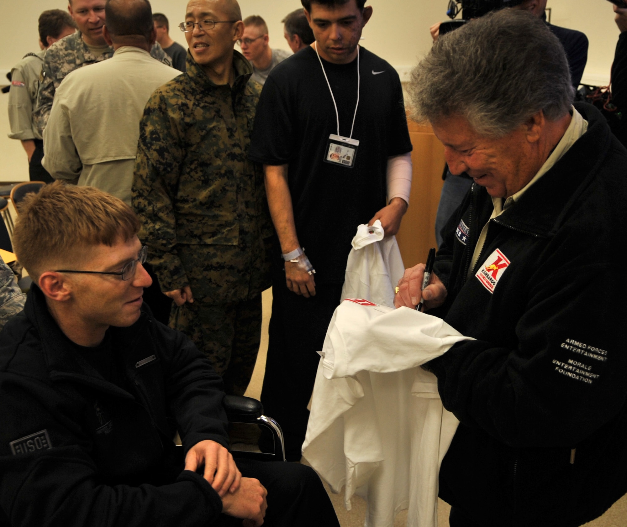 Mario Andretti, Indy 500, Daytona 500, and Formula 1 champion, autographs t-shirts for wounded warriors during the Indy 500 Centennial Tour, Ramstein Air Base, Germany, Jan. 14, 2011. The Indy 500 Centennial tour brings Indy racing teams to Europe and the Middle East over a 10 day tour to honor and boost morale for service members and their families. (U.S. Air Force photo by Senior Airman Caleb Pierce)