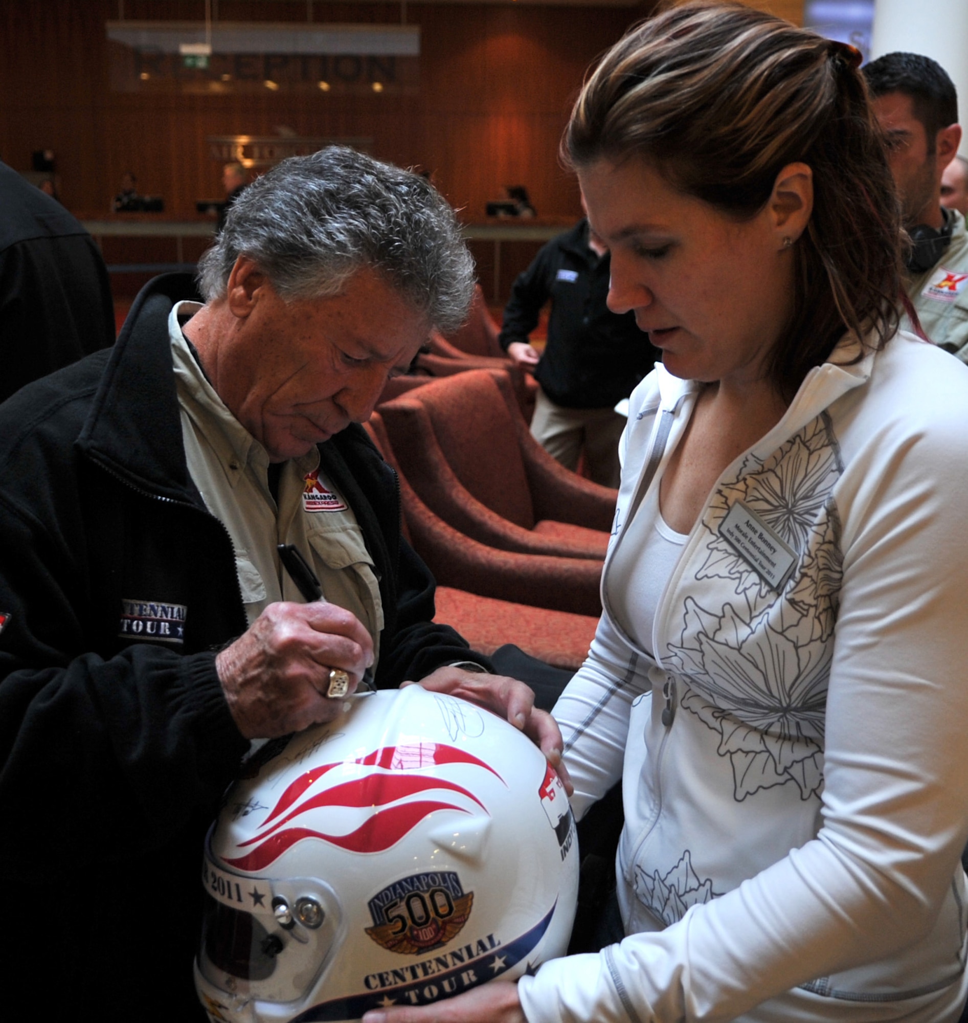 Mario Andretti, Indy 500, Daytona 500, and Formula 1 champion, autographs a helmet during the Indy 500 Centennial Tour, Ramstein Air Base, Germany, Jan. 14, 2011. The Indy 500 Centennial tour brings Indy racing teams to Europe and the Middle East over a 10 day tour to honor and boost morale for service members and their families. (U.S. Air Force photo by Senior Airman Caleb Pierce)