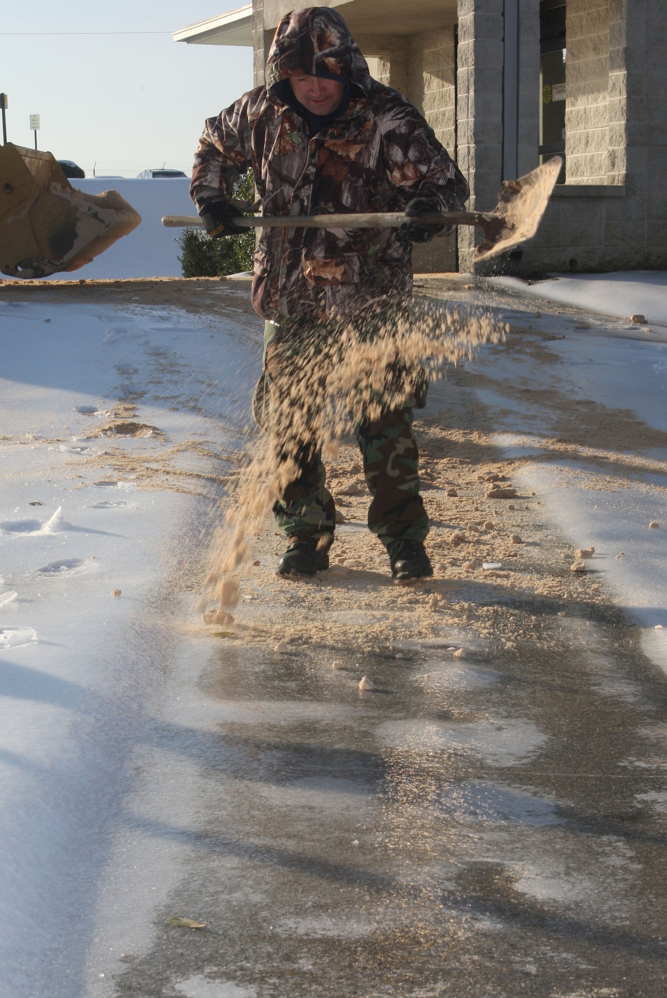 Grounds crews work spreading sand onto sidewalks and spaces where ice may be a hazard Jan 12 after the base was covered in a blanket of ice and snow following a massive winter storm that hit the southeastern region Jan 10. (U.S. Air Force Photo/Don Peek)