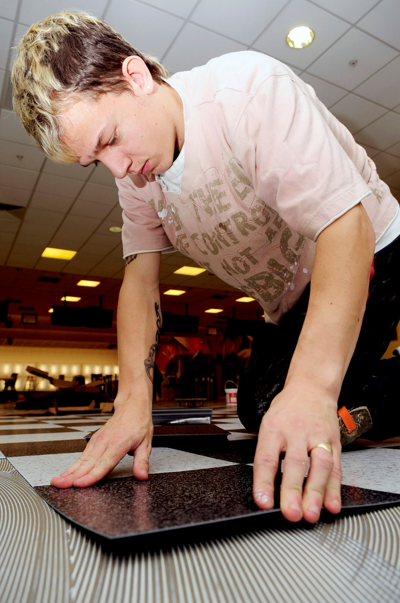RAF MILDENHALL, England -- Sam Hawkes, a local contractor, lays vinyl tile at the Bowling Center Jan. 13, 2011. This is the first time the Bowling Center's floor has been redone in six years since the center first opened. (U.S. Air Force photo/Senior Airman Ethan Morgan) 