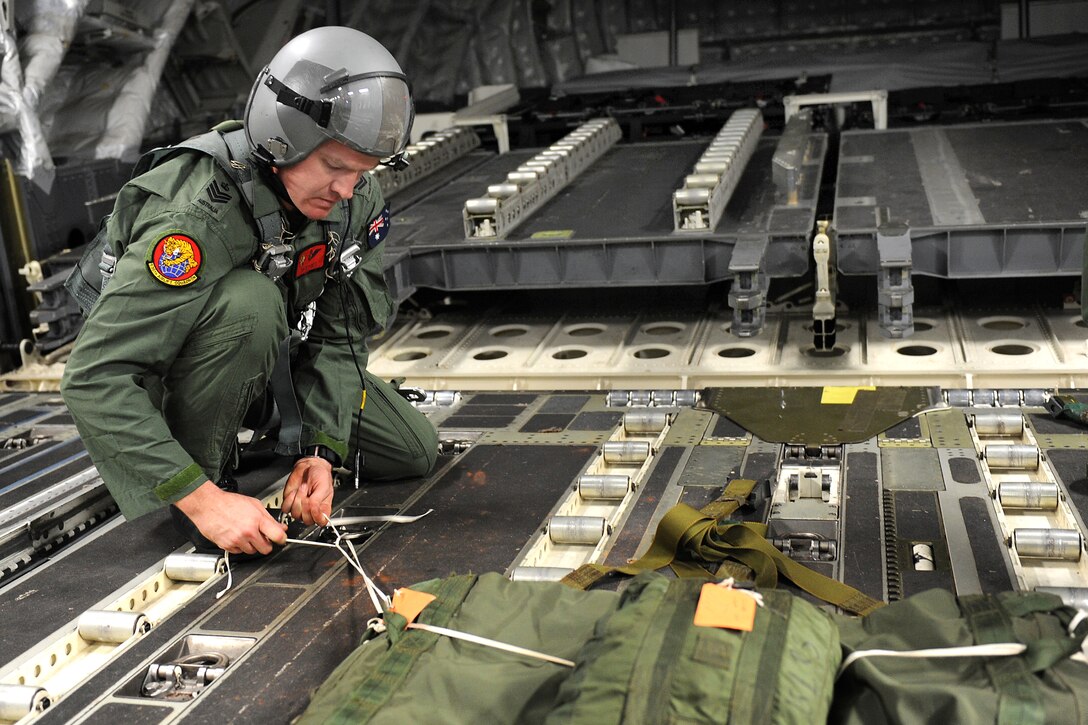 Royal Australian Air Force Flight Sgt. Dave Pyatt secures a parachute to a heavy airdrop training pallet while in flight for a mission over Andersen Air Force Base, Guam, Jan. 11, 2011. Pyatt, a loadmaster, has been assigned to the 535th Airlift Squadron as part of an exchange program with the U.S. Air Force.