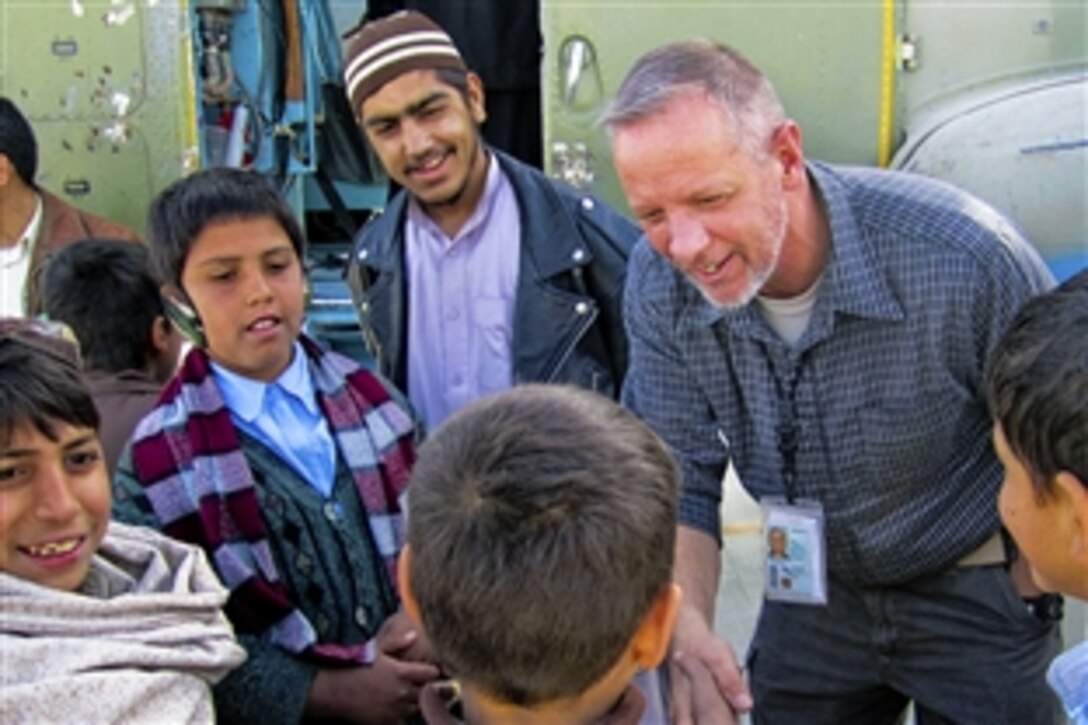 Thomas Wiglesworth, a teacher with the Department of Defense Education Activity, speaks English with students as they explore an aircraft during a Kandahar, Afghanistan, open house, Jan. 1, 2011. Wiglesworth is deployed in Afghanistan for a year to teach English to Afghan security forces and other personnel.