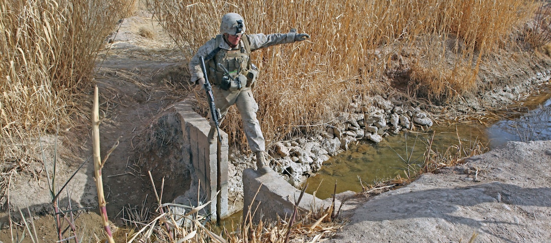 Lance Cpl. Glenn A. Cocagne, a team leader with Weapons Company, 2nd Battalion, 9th Marine Regiment, carefully steps across an open causeway to cross a canal during Operation Integrity, in Marjah, Helmand Province, Afghanistan, Jan. 15. The main purpose of the operation was to successfully cordon off a suspected hotspot for Taliban activity, search for weapon and IED caches, disrupt enemy logistical operations and gather census data on locals in the region of Sistani.::r::::n::::r::::n::