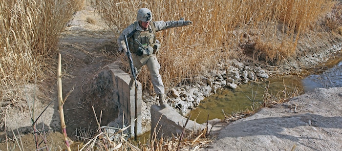 Lance Cpl. Glenn A. Cocagne, a team leader with Weapons Company, 2nd Battalion, 9th Marine Regiment, carefully steps across an open causeway to cross a canal during Operation Integrity, in Marjah, Helmand Province, Afghanistan, Jan. 15. The main purpose of the operation was to successfully cordon off a suspected hotspot for Taliban activity, search for weapon and IED caches, disrupt enemy logistical operations and gather census data on locals in the region of Sistani.::r::::n::::r::::n::