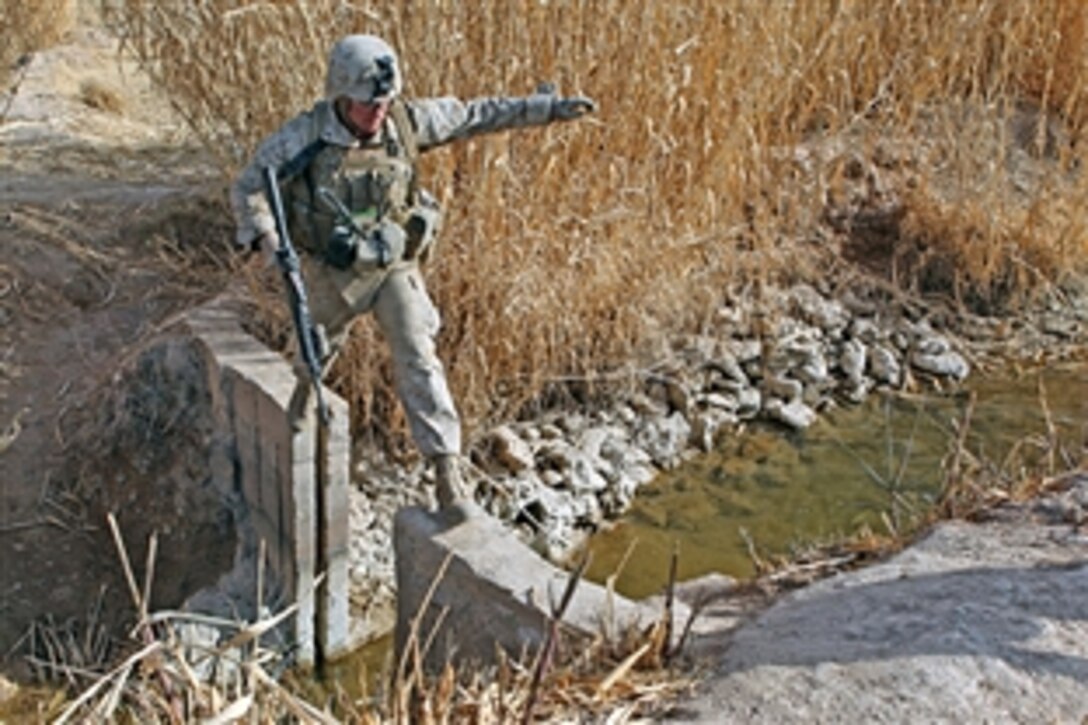 U.S. Marine Corps Lance Cpl. Glenn A. Cocagne carefully steps across an open causeway to cross a canal during Operation Integrity, in Marjah, Helmand province, Afghanistan, Jan. 15, 2011. Cocagne is assigned to Weapons Company, 2nd Battalion, 9th Marine Regiment.