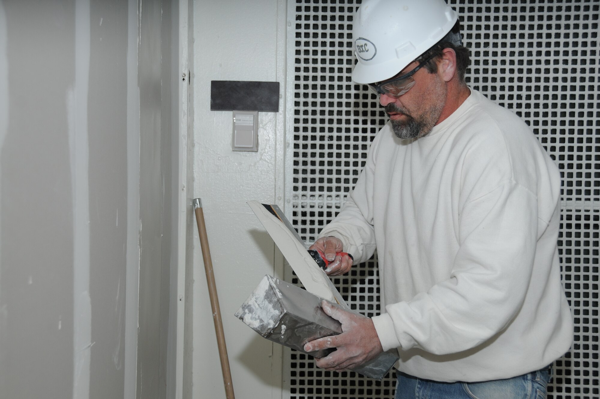 Dry wall technician David Lynn from Birmingham Industrial Construction applies skim
coat on wallboard on the second floor of Allee Hall Friday.  (U.S. Air Force photo by Kemberly Groue)
