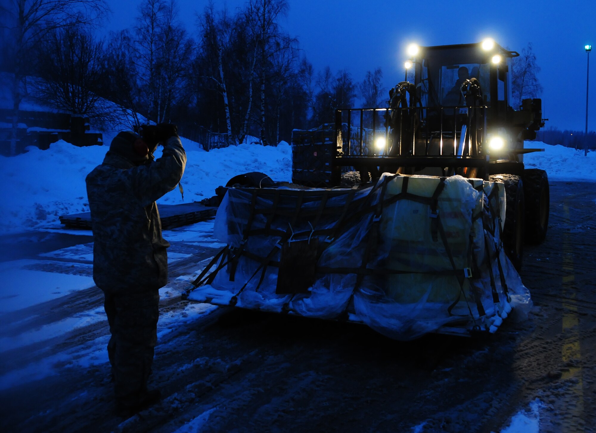 Tech. Sgt. Carlos Cardenas guides a forklift being driven by Senior Airman Scott Knight Jan. 7, 2011, at Lithuania Air Base, Lithuania. Sergeant Cardenas is an air transportation craftsman with the 493rd Expeditionary Fighter Squadron Redeployment Action Team. Airman Knight is an air transportation journeyman with the 493rd EFS RAT. (U.S. Air Force photo/Staff Sgt. Stephen Linch)
 