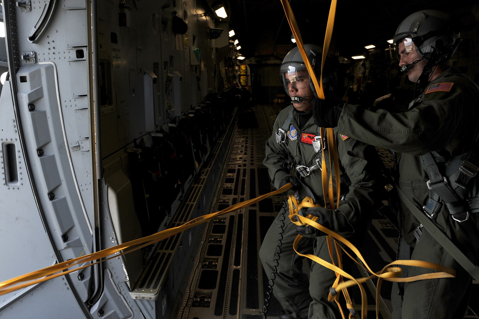 Staff Sgt. Danny Hollister and Senior Master Sgt. Chuck Baker, 535th Airlift Squadron loadmasters, retrieve static lines from the troop door after the final three jump masters jumped from a C-17 Globemaster III from Joint Base Pearl Harbor-Hickam, Hawaii, Jan. 13. Airmen from the 36th Contingency Response Group landed on the Andersen Air Force Base, Guam, drop zone during static line jump proficiency training.  The Hickam aircrew provided four separate jumps for the 36th CRG Airmen. (U.S. Air Force photo/Staff Sgt. Mike Meares)