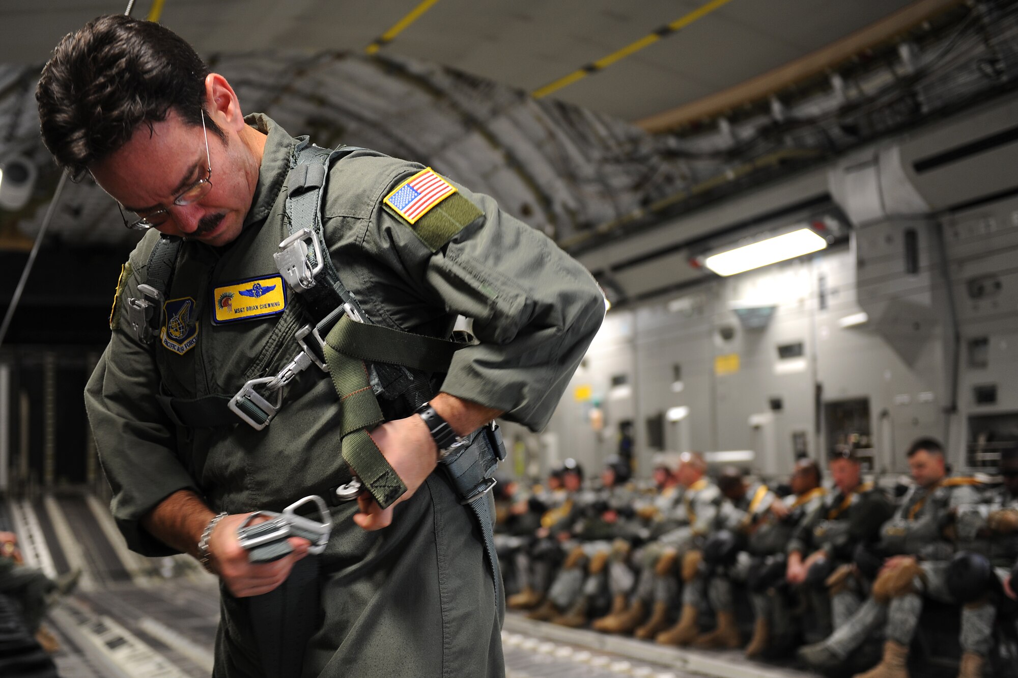 Master Sgt. Brian Chewning, 535th Airlift Squadron C-17 Globemaster III loadmaster, secures a safety harness prior to opening the troop doors for the 36th Contingency Response Group static line jumpers Jan.13. Hickam aircrew provided four static line jumps for the 36th CRG?s proficiency training over two separate days. (U.S. Air Force photo/Staff Sgt. Mike Meares)