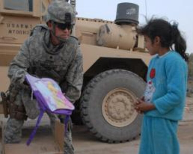 U.S. Air Force Lt. Col. Tom Walsh, Echelon Above Division-Advise and Train senior advisor and Benbrook, Texas, native, hands a “tinkerbell” backpack to a local Iraqi girl, Dec. 16, at Ur Elementary School near Tallil Air Base, Iraq. Walsh is deployed from the Pentagon. (Courtesy Photo)


