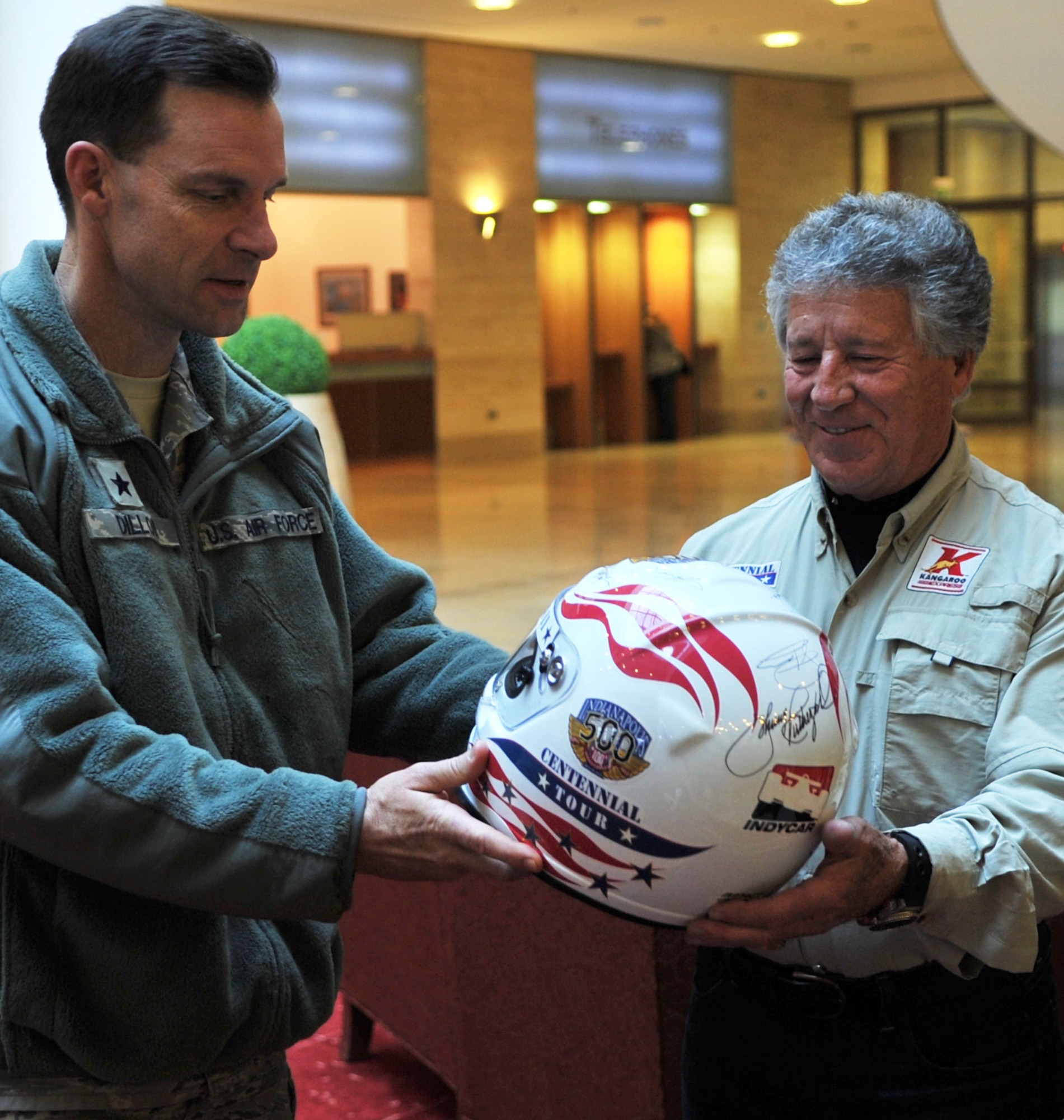 Brig. Gen. Mark Dillon receives an autographed helmet from Mario Andretti, an Indy 500, Daytona 500 and Formula 1 champion, during the Indy 500 Centennial Tour, Jan. 14, 2011, at Ramstein Air Base, Germany. The Indy 500 Centennial tour brings Indy racing teams to Europe and the Middle East over a 10-day tour to honor and boost morale for service members and their families. General Dillon is the 86th Airlift Wing commander (U.S. Air Force photo/Senior Airman Caleb Pierce)