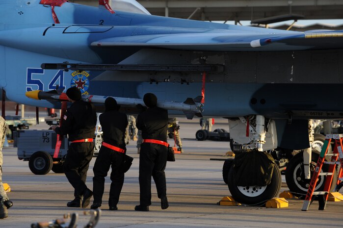 NELLIS AIR FORCE BASE, Nev. --  Staff Sgt. Eric Crawley, Senior Airman Phillip Hohner, and Senior Airman Jolin Daigneault, 757th Aircraft Maintenance Squadron aircraft armament systems weapons load team, load an AIM-9 air to air missile on a F-15 Eagle during a weapons load competition on the Nellis flightline Jan. 14. Weapons load competitions are conducted quarterly to keep Airmen sharp and recognize superior performers. Weapons load teams are evaluated for use of the checklist, safety, and overall speed. (U.S. Air Force photo by Airman 1st Class George Goslin)