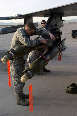 NELLIS AIR FORCE BASE, Nev. --  Staff Sgt. William Strong, 57th Aircraft Maintenance Squadron aircraft armament systems journeyman, secures a GBU-12 laser-guided bomb to an F-16 Fighting Falcon during a weapons load competition on the Nellis flightline Jan. 14. Weapons load competitions are conducted quarterly to keep Airmen sharp and recognize superior performers. Weapons load teams are evaluated for use of the checklist, safety, and overall speed. (U.S. Air Force photo by Airman 1st Class George Goslin)