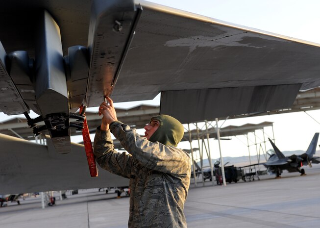 NELLIS AIR FORCE BASE, Nev.-- Airman 1st Class Jeff Kalsbeek, 757th Aircraft Maintenance Squadron, armament systems specialist, prepares to load weapons onto the F-15 Eagle during a weapons load competition on the Nellis flightline Jan. 14. Weapons load competitions are conducted quarterly to keep Airmen sharp and recognize superior performers. Weapons load teams are evaluated for their use of the checklist, safety, and overall speed. (U.S. Air Force photo by Airman 1st Class Matthew Lancaster)