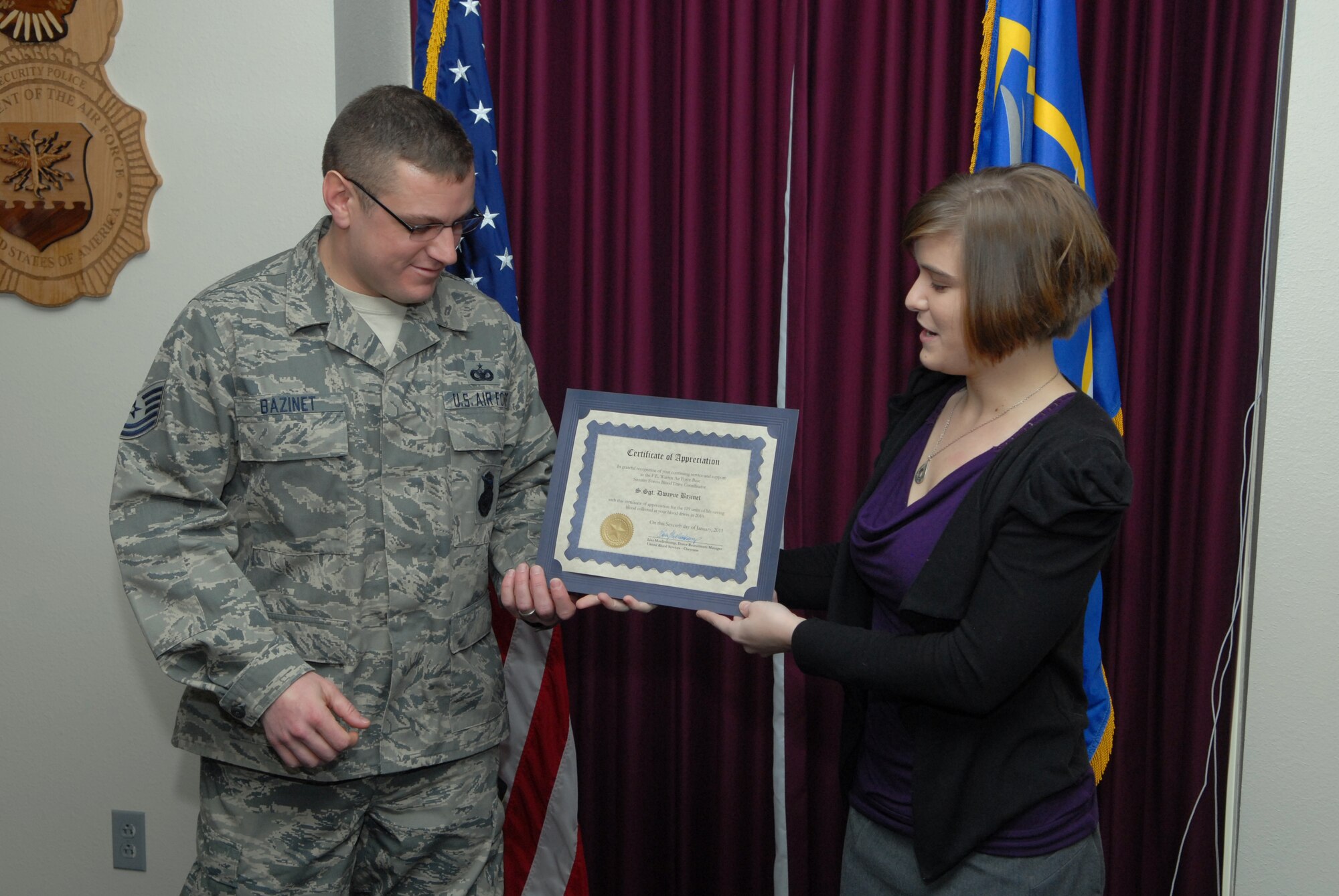 Molly Stroud, United Blood Services donor recruiter, presents Tech. Sgt. Dwayne Bazinet, 90th Security  Forces Group,  a certificate Jan. 7 honoring the 90th SFG for the amount of blood the group donated throughout 2010. Ms. Stroud says that of the 509 units of blood donated on base last year, 119 came from the 90th SFG. (U.S. Air Force photo by R.J. Oriez)