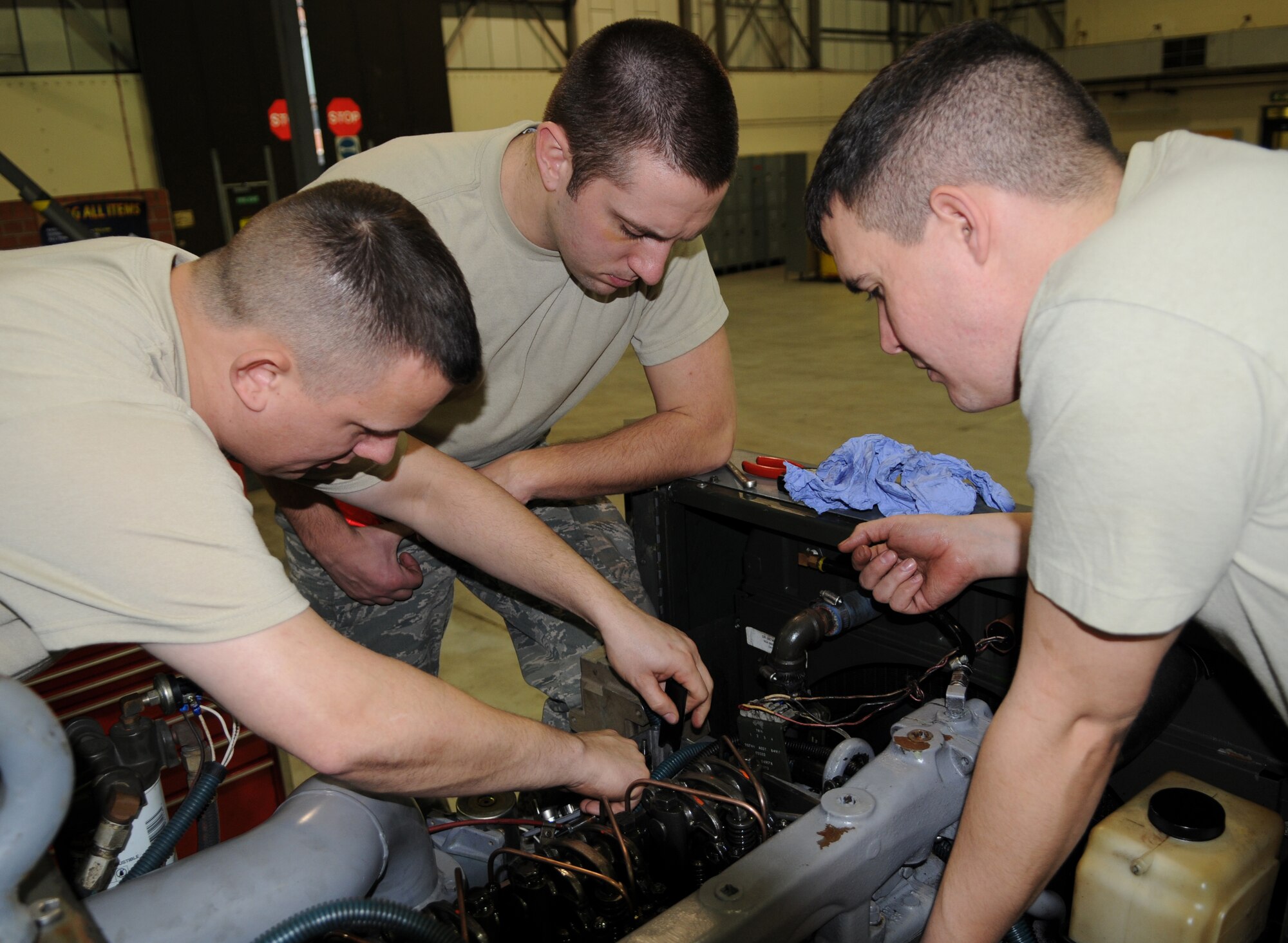 RAF MILDENHALL, England -- Staff Sgt. Tony Shepherd (left), 100th Maintenance Squadron Aerospace Ground Equipment technical instructor, demonstrates how to properly check the space in a generator gap on an A/M32A-86 diesel generator to Airman 1st Class Chris Corley (center) and Senior Airman John Gardner, 100th MXS AGE mechanics, during a refresher field training course Jan. 14, 2011 at the AGE flight. The refresher training is held monthly to ensure all AGE mechanics are familiar with operating procedures. (U.S. Air Force photo/Airman 1st Class Rachel Waller)