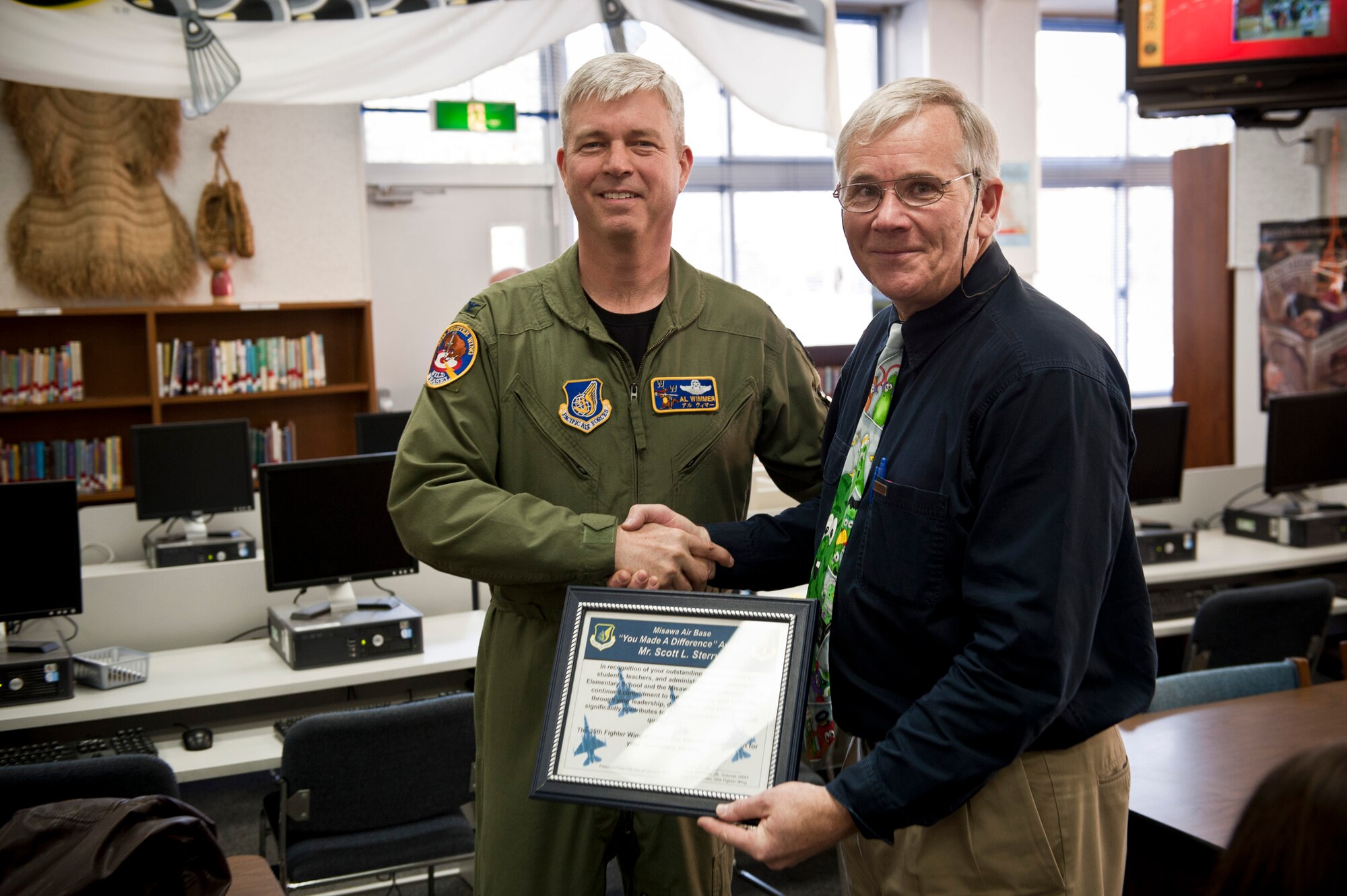 In a surprise presentation, U.S. Air Force Col. Van Wimmer, 35th Fighter Wing vice commander, presents the "You Made a Difference" award to Scott Sterry, Cummings Elementary School principal, during a teacher meeting at Cummings Elementary School, Misawa Air Base, Japan; Jan. 11, 2011. The Edgren High School and Sollars Elementary School principals nominated him, citing his selfless passion for education, commitment to his students and faculty as well as his compassionate leadership. (U.S. Air Force photo by Staff Sgt. Samuel Morse/Released)