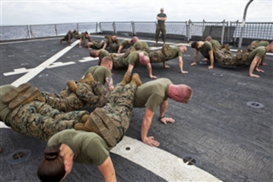 U.S. Marines execute squad push-ups as body-hardening training while aboard the dock landing ship USS Gunston Hall in the Southern Command area of responsibility, Jan. 17, 2011. The Marines, assigned to Marine Wing Support  Squadron 271, Logistics Command Element, Headquarters Command Element, will head to Central and South America to participate in Southern Partnership exercises.