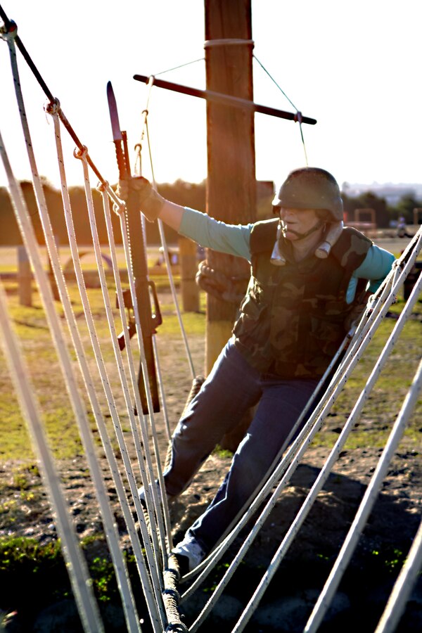 Helen Harris, counselor at Elgin High school, Elgin, Ill., crosses a rope bridge over a pit while trying to maintain a hold on her rubber rifle. The educators spend three days observing Marine training so that they can offer their students informative insight when making the decision to serve in the Marine Corps.