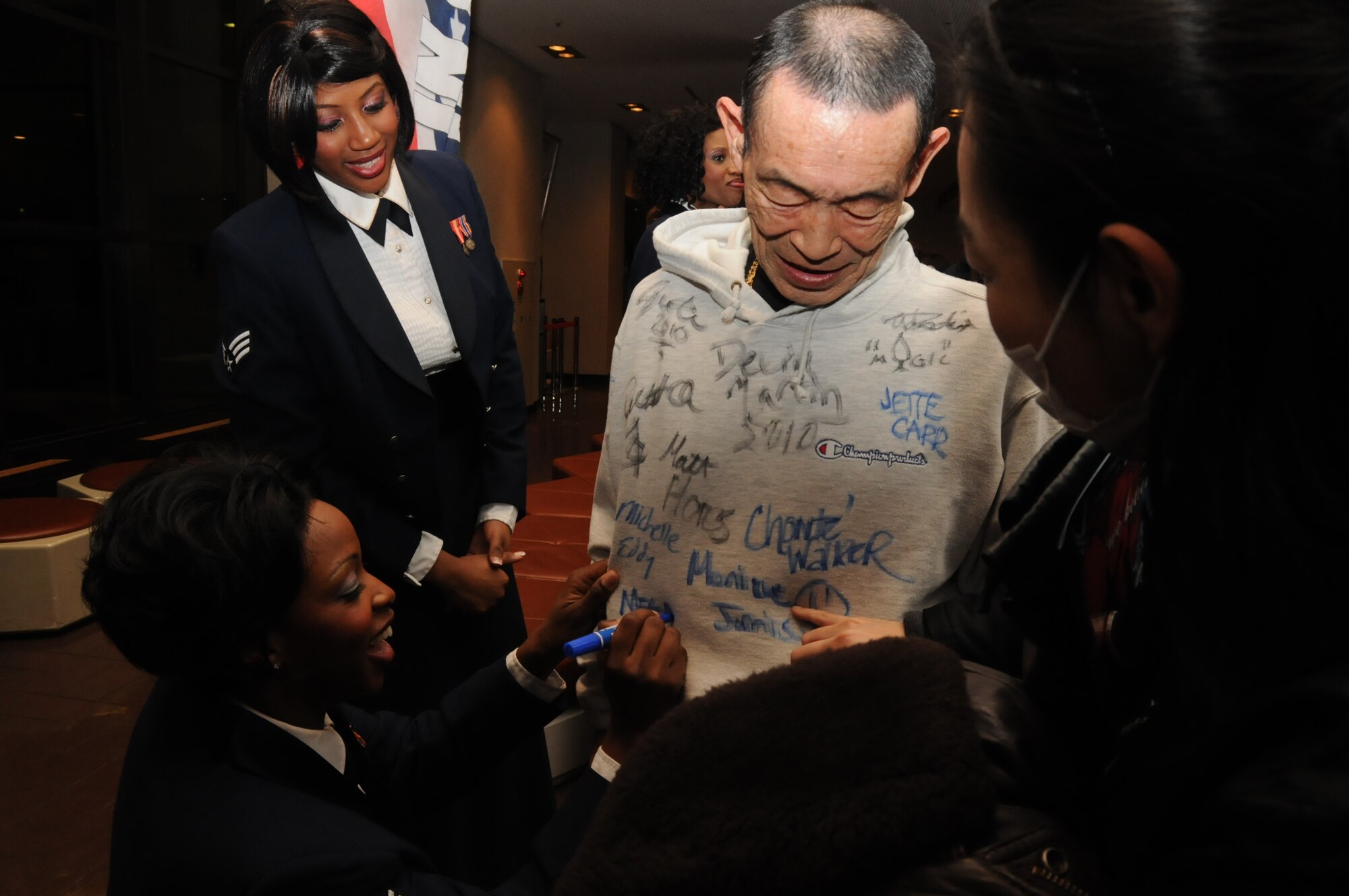 Members of the Tops In Blue 2010 World Tour sign the shirt of a Japanese man following a show at the Misawa Civic Center Jan. 18, 2011. Holding the show at an off-base venue allowed members of the local community to attend along with base members and their families. (U.S. Air Force photo by Staff Sgt. Rachel Martinez/Released)