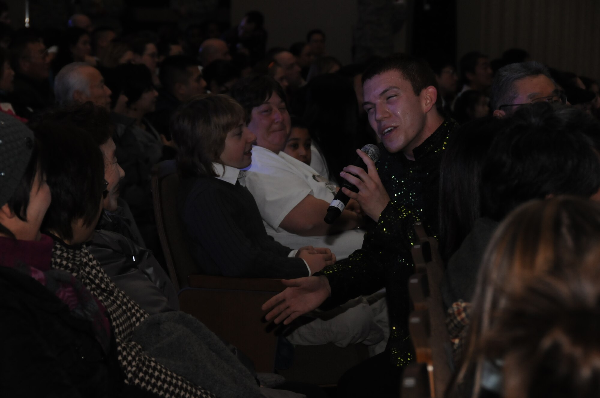 Airman 1st Class Matthew Flores, a Tops In Blue member, serenades a member of the audience during a performance at the Misawa Civic Center Jan. 18, 2011. Performers entered the audience at several points during the show. (U.S. Air Force photo by Staff Sgt. Rachel Martinez/Released)